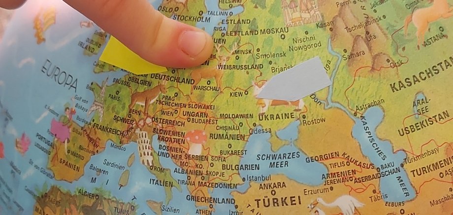 Ein KInderfinger zeigt auf einer Weltkugel auf die Ukraine.
