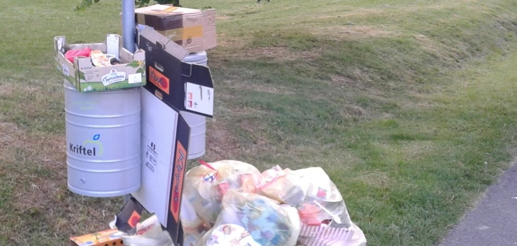 Müll unter einem überfüllten Mülleimer im Freizeitpark.