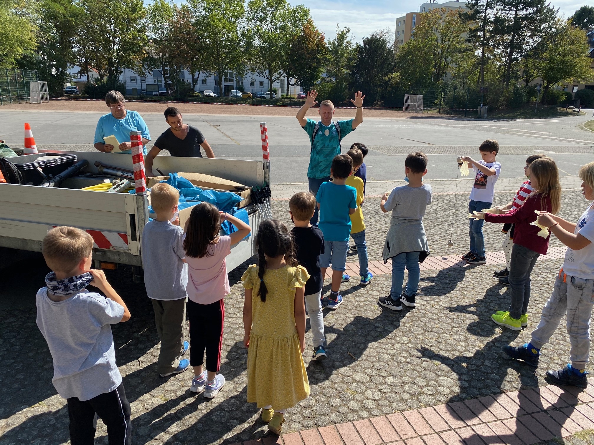 Mitarbeiter des bauhofes teilen an die Kinder Zangen, Säcke und Handschuhe aus.