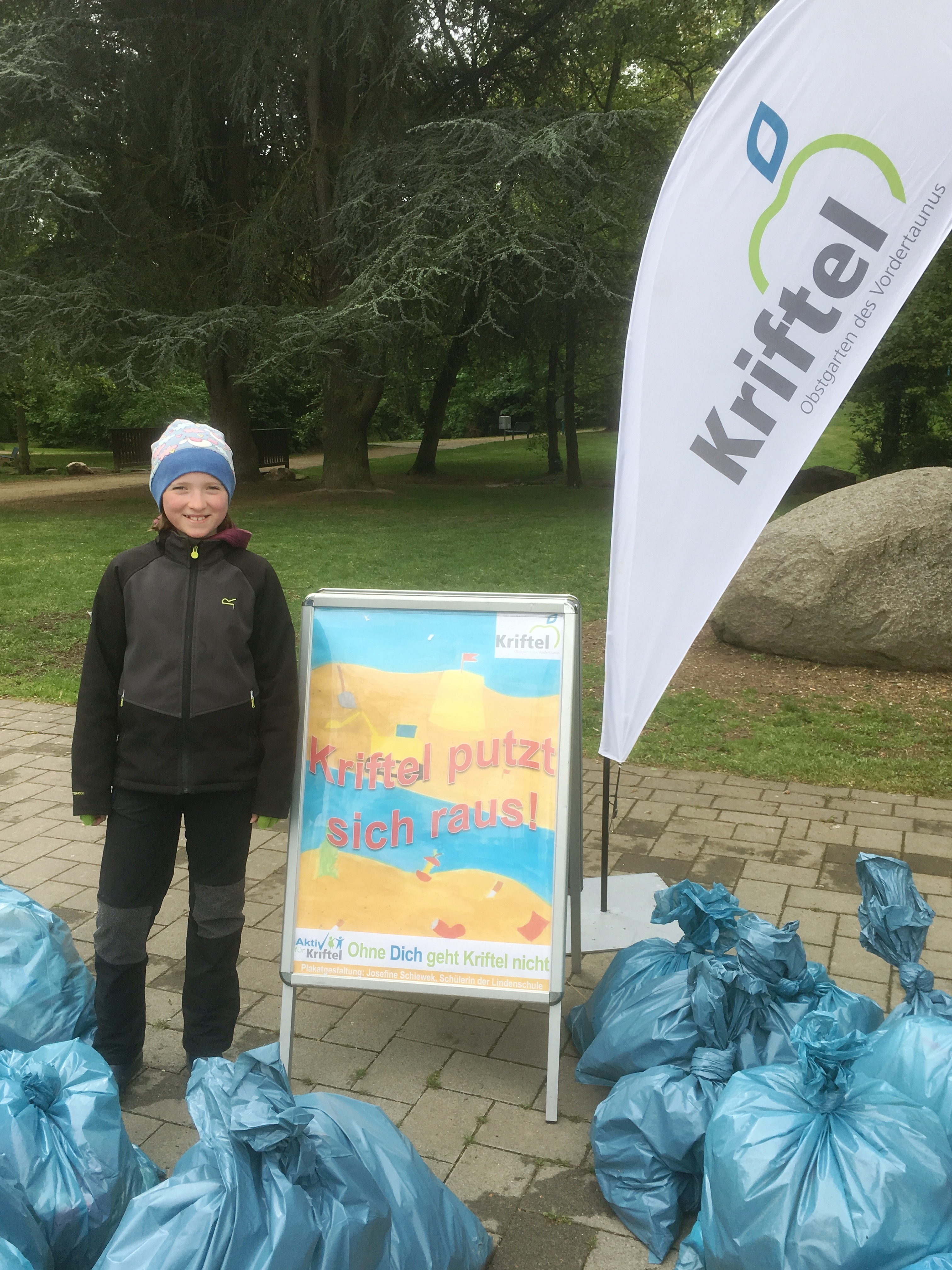 Josephine Schiwek neben dem von ihr entworfenen Plakat und zehn Säcken voller Müll.