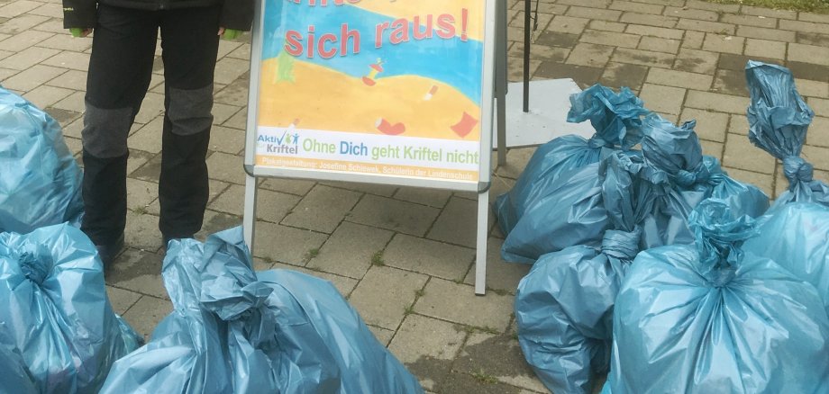 Josephine Schiwek neben dem von ihr entworfenen Plakat und zehn Säcken voller Müll.