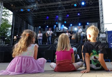 Kinder sitzen auf dem Boden vor der Bühne.