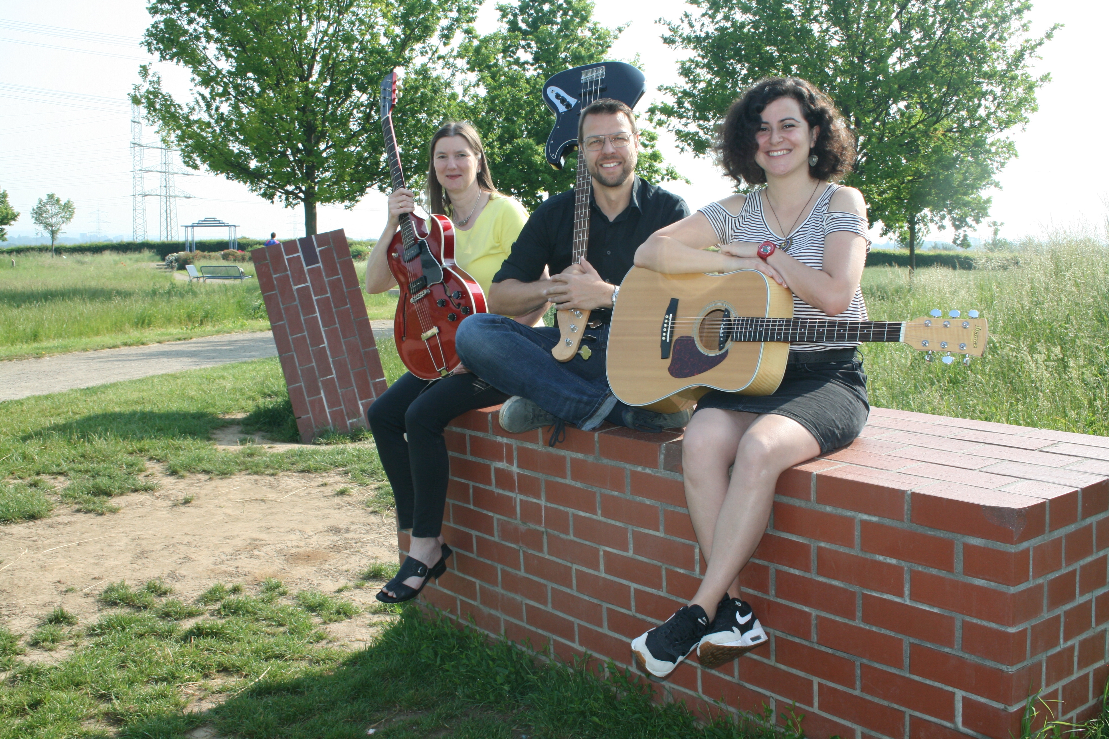 Drei MItglieder der Band MissTune(d) sitzen auf einem Ziegelblock im Ziegeleipark.