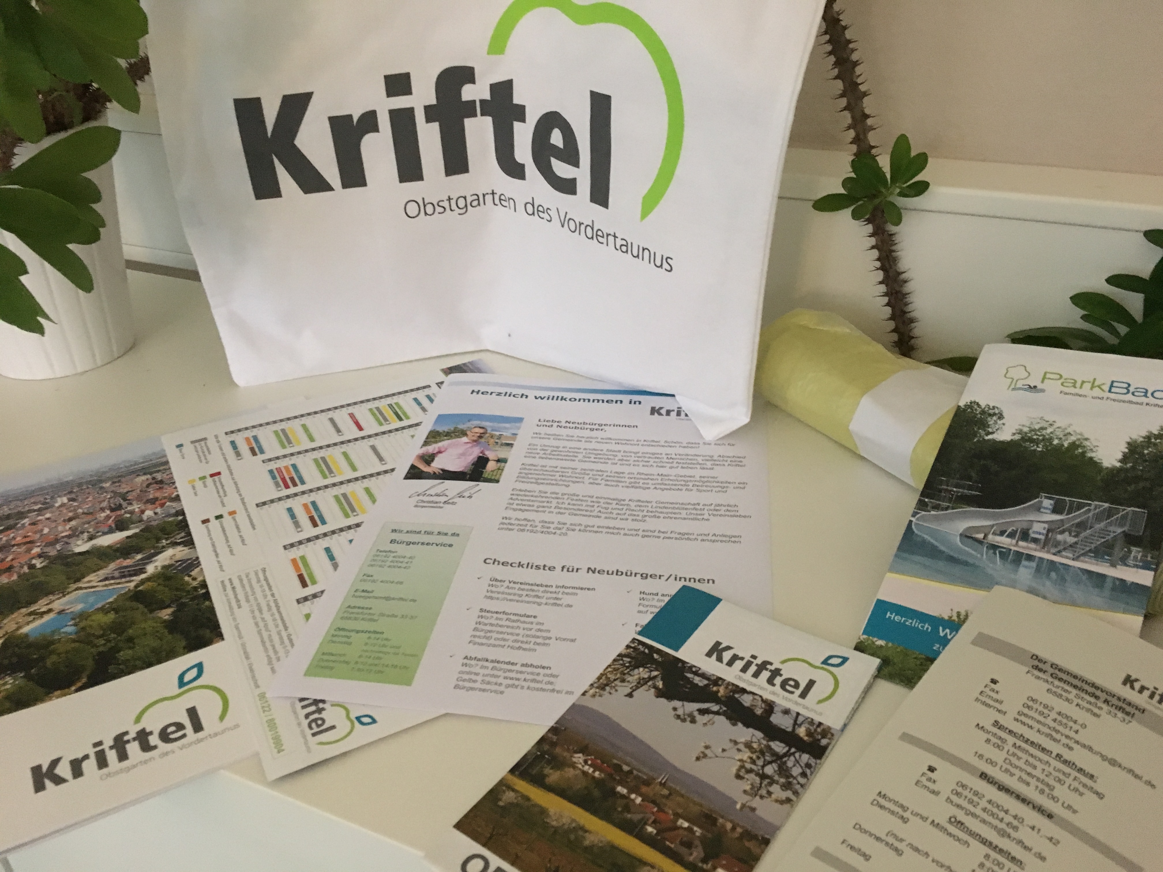 Der neue Einkaufsbeutel mit Kriftel-Logo und davor Imagebroschüre, Abfallkalender und Neubürgerbrief.