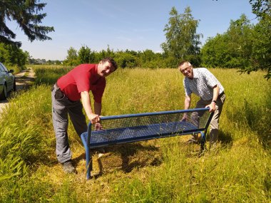 Jirasek und Bauhof-Mitarbeiter versuchen, die neue Bank hochzuheben.