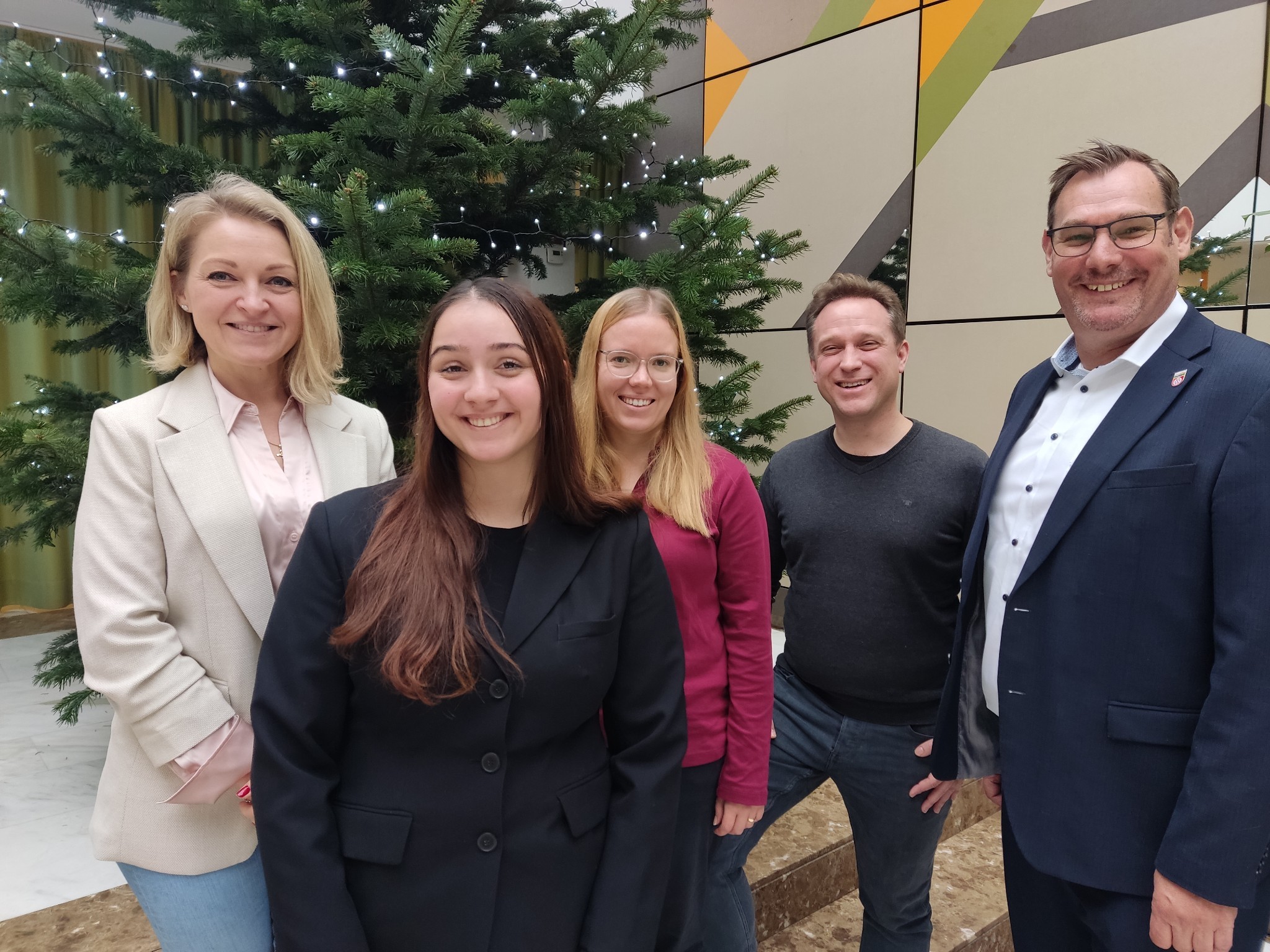 Die neuen Mitarbeiterinnen mit der Rathausspitze vor dem Tannenbaum.