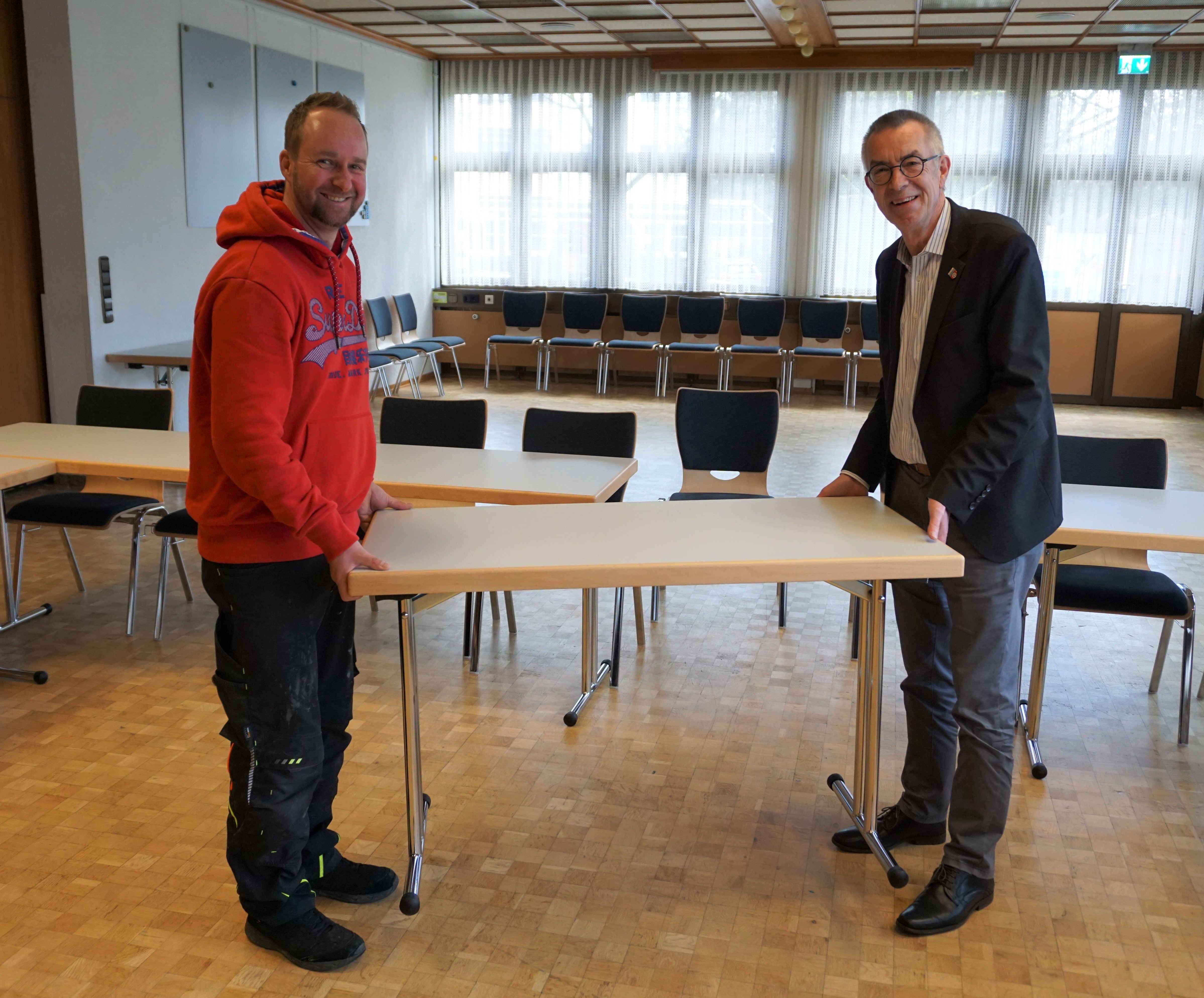 Jirasek und Hausmeister tragen einen neuen Tisch.