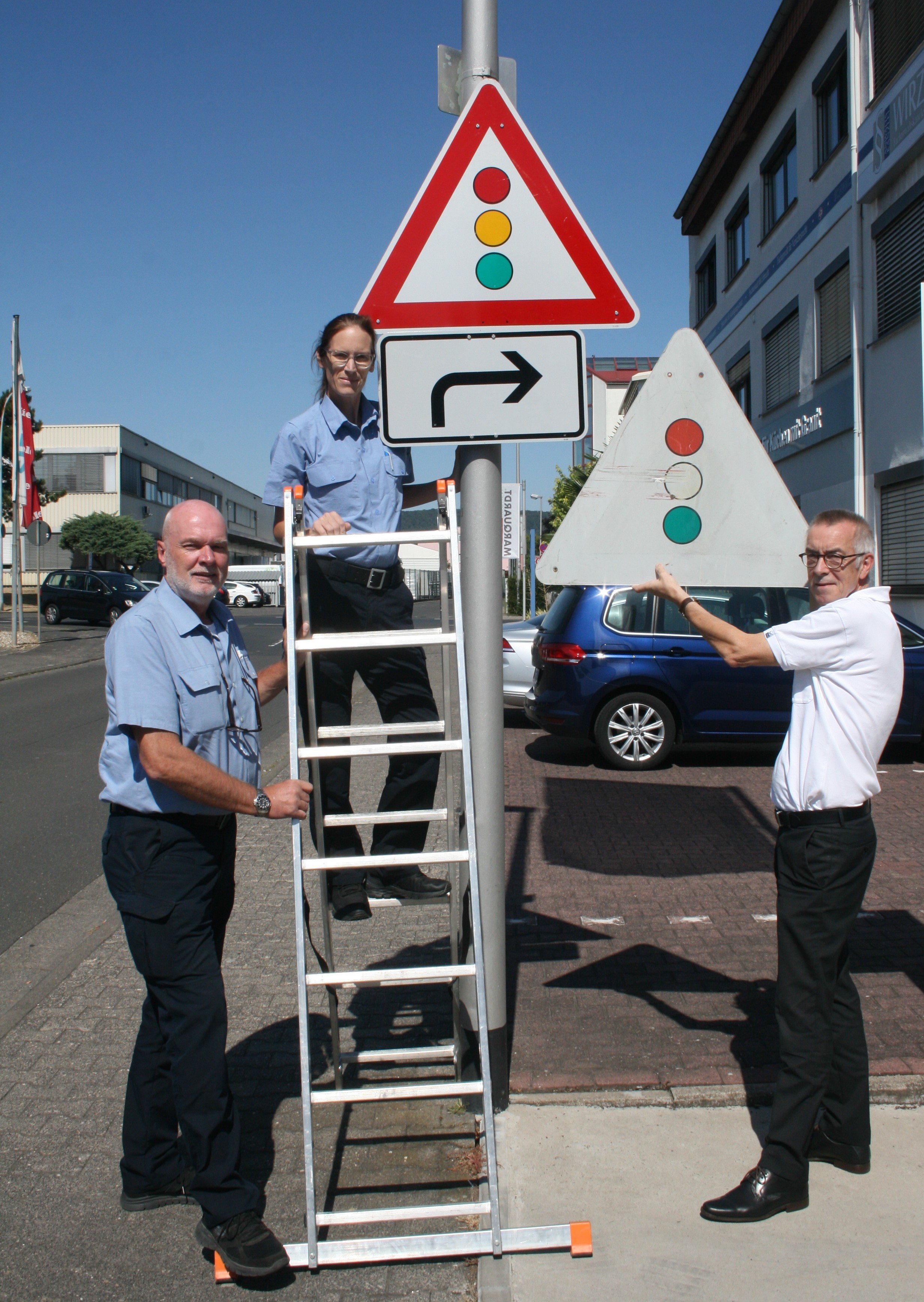 Die Hilfspolizisten mit einem neuen und einem alten Ampelschild.