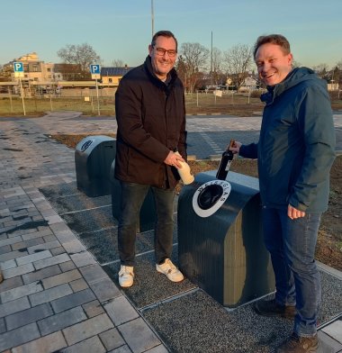 Seiutz und Mohr werfen Flaschen in neuen Container.