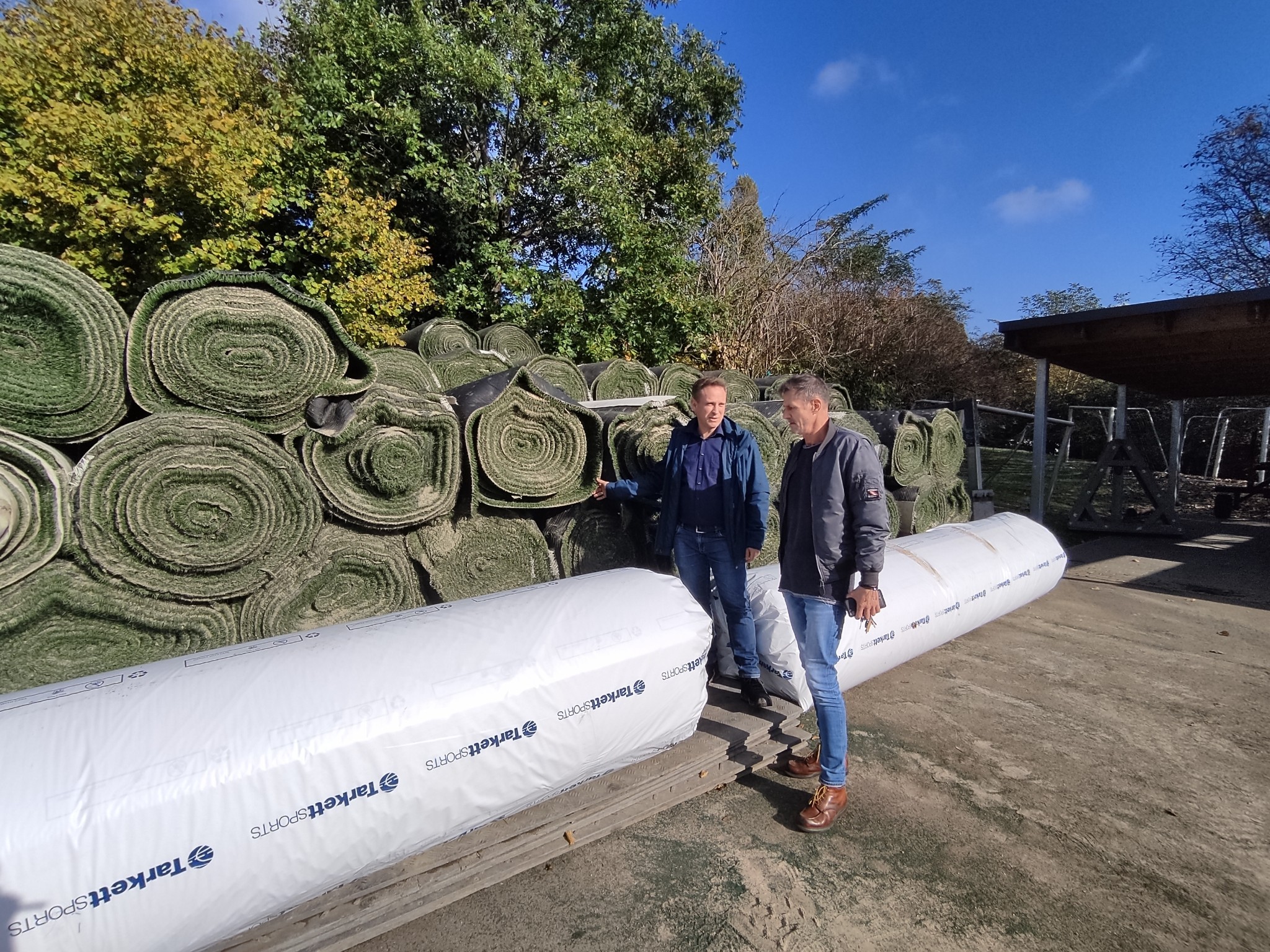 Martin Mohr und Michael Knittel vor den neuen und alten Kunstrasen-Rollen.