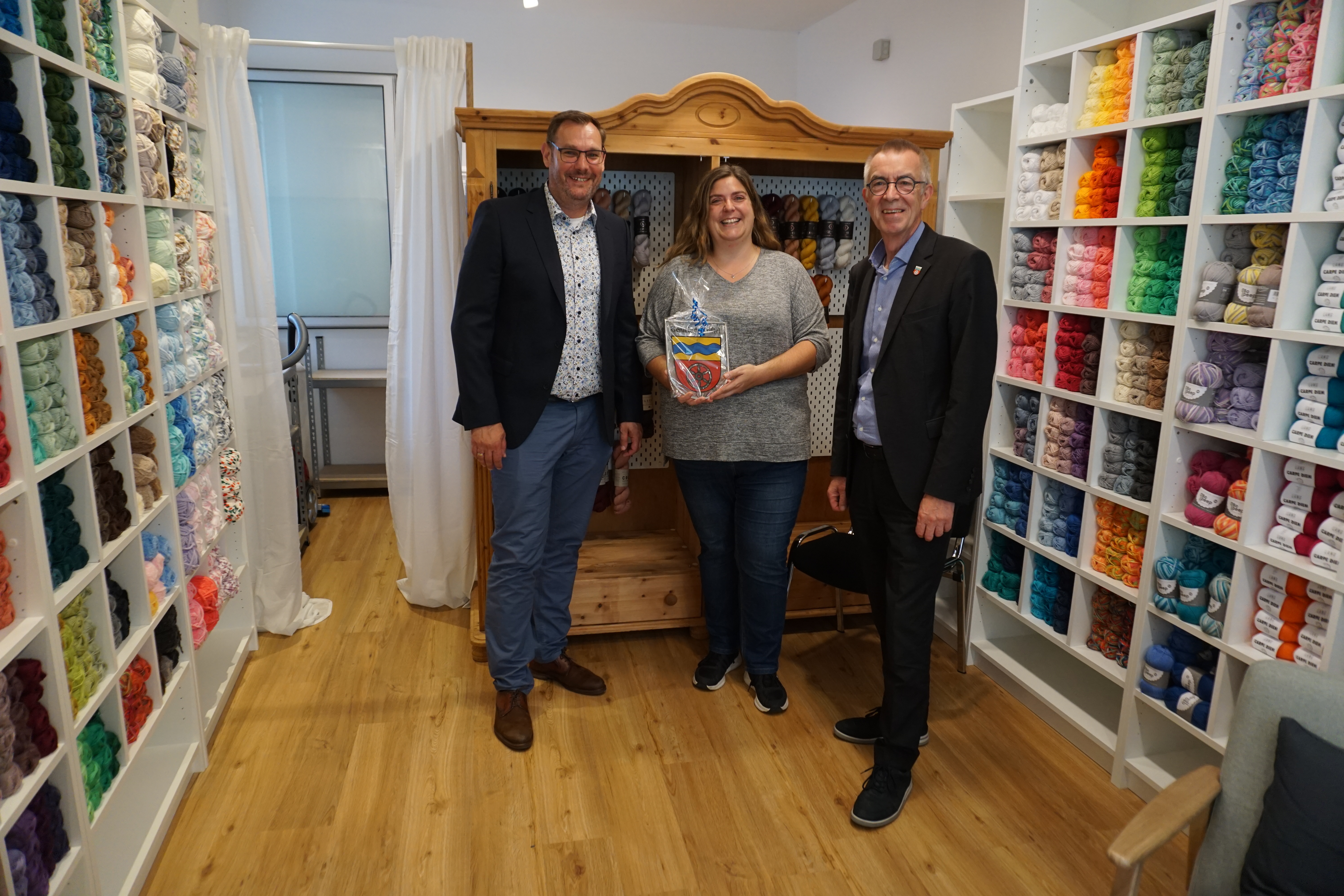 Seitz, Jirasek und Manuela Sittig vor Regalen voller Wolle.