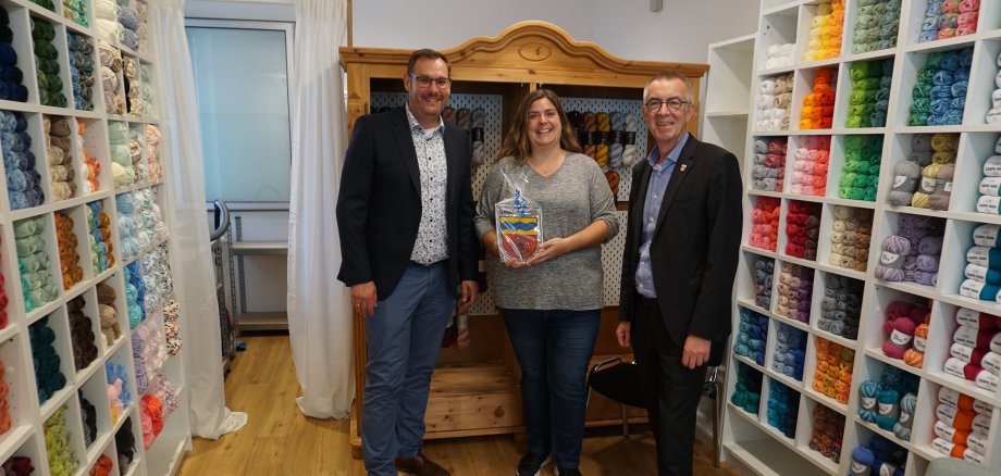 Seitz, Jirasek und Manuela Sittig vor Regalen voller Wolle.