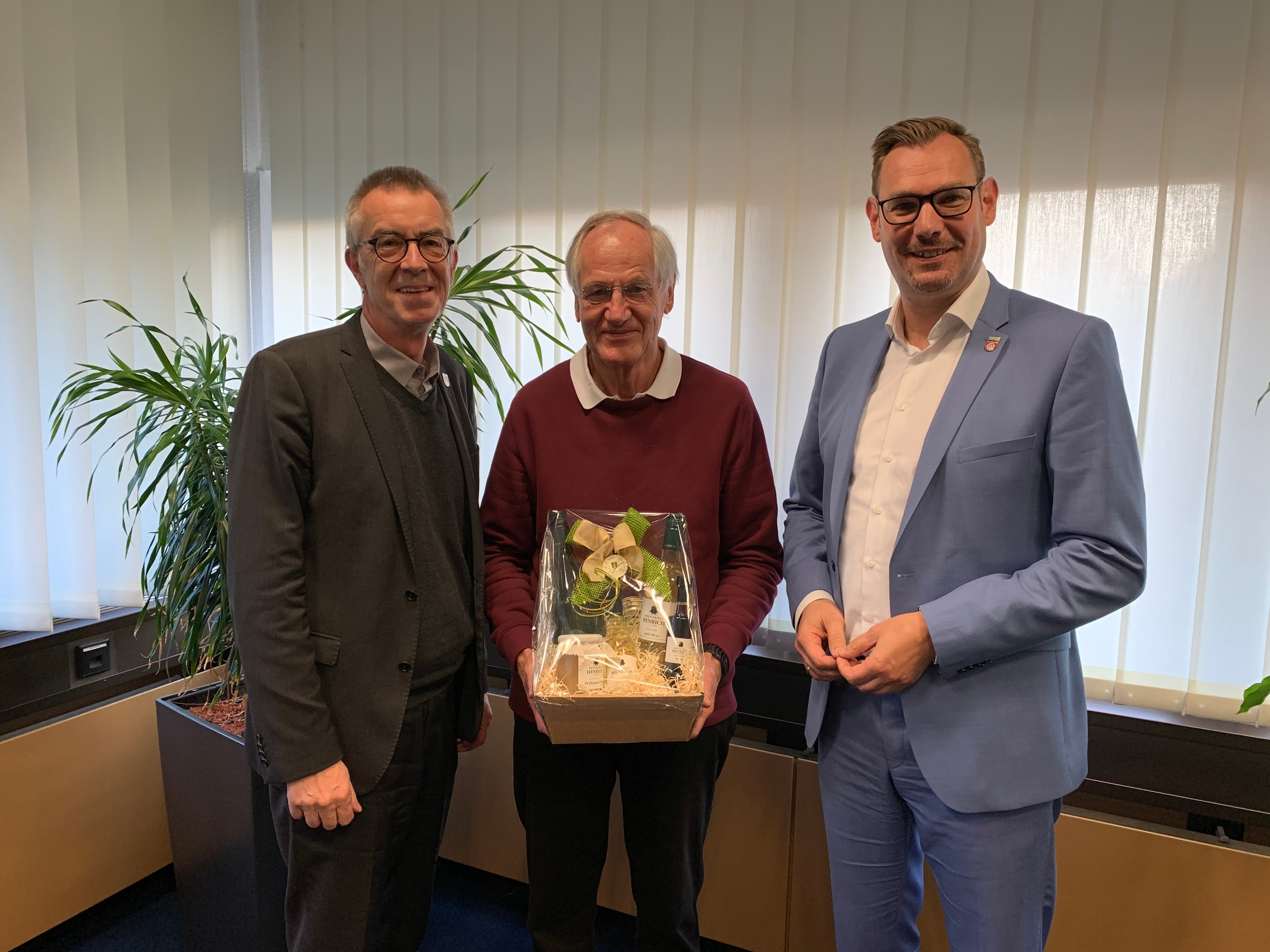Manfred Neumann mit Geschenk inmitten von Franz Jirasek und Christian Seitz.