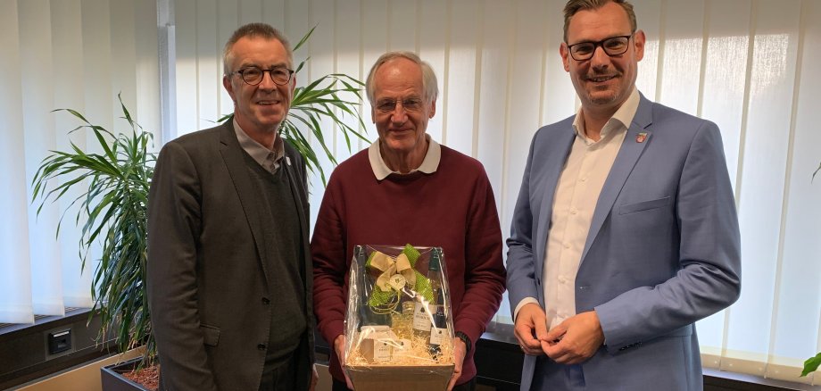Manfred Neumann mit Geschenk inmitten von Franz Jirasek und Christian Seitz.