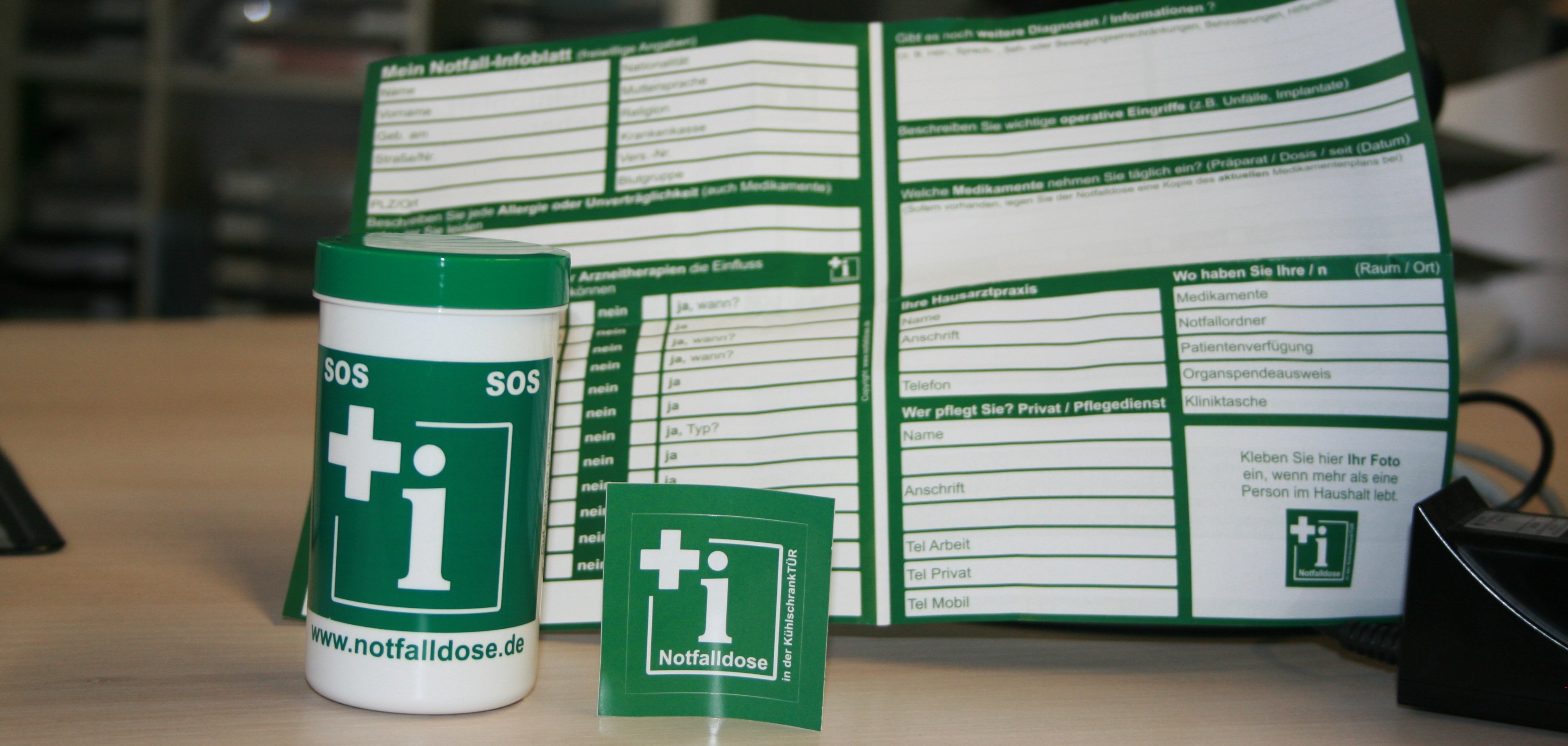 Die grüne Notfalldose und ihr Inhalt: Ein Dokument zum Ausfüllen und Aufkleber.