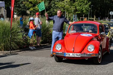 Bürgermeister Seitz mit Startfahne neben Oldtimer.