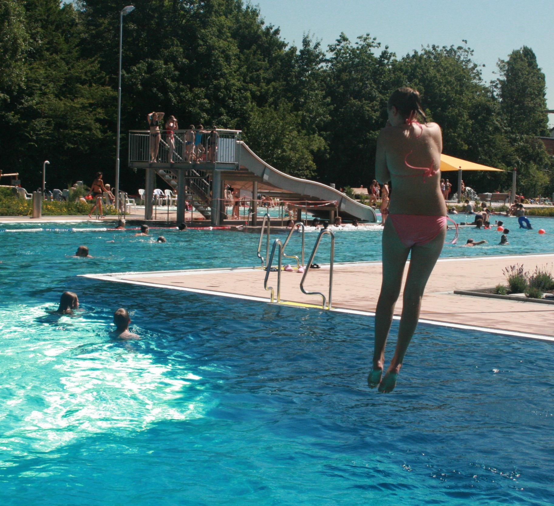 Ein Kind springt vom Zwei-Meter-Brett.