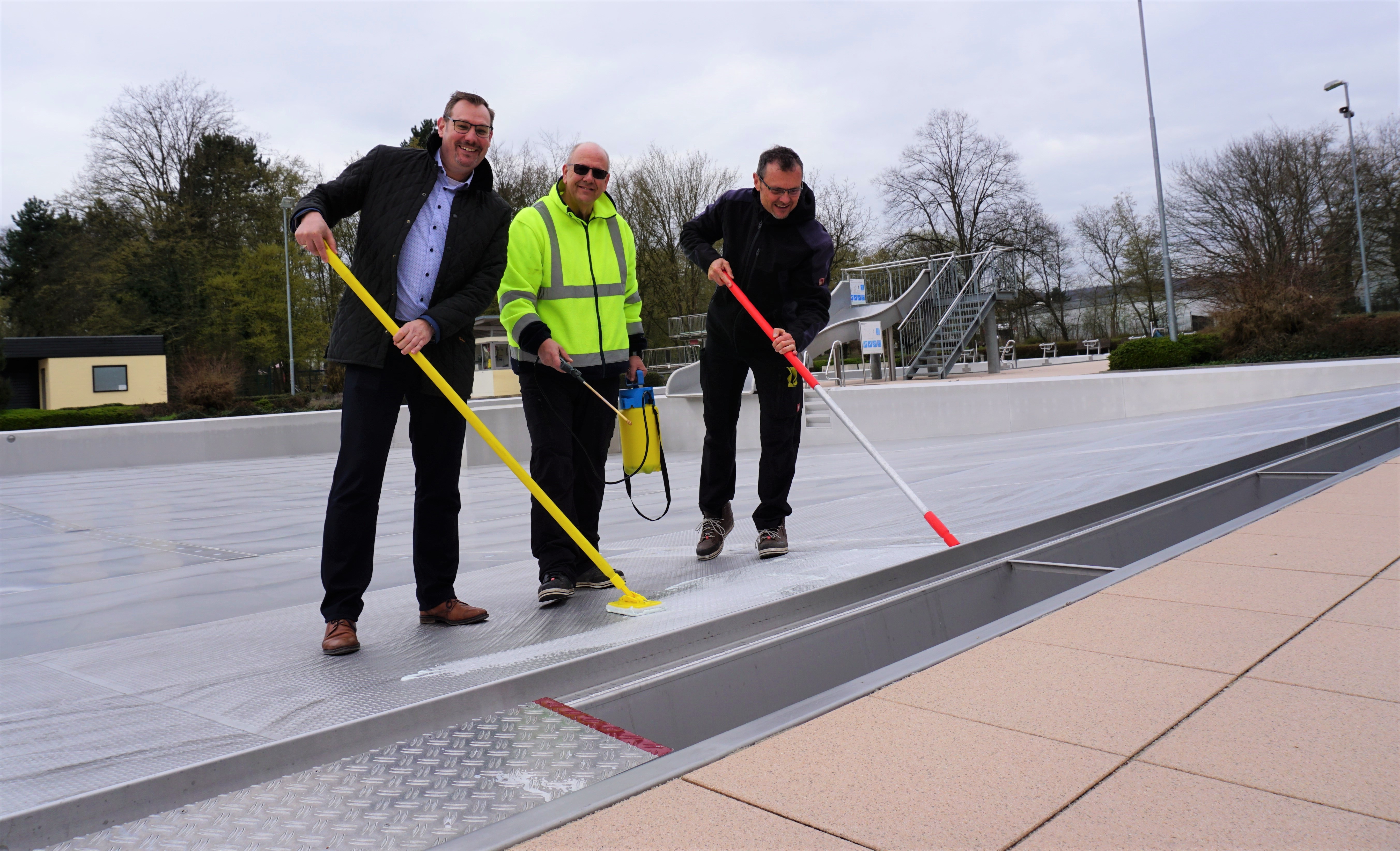 Bürgermeister mit Schwimmmeistern und Schrubber.