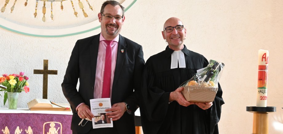 Christian Seitz und Pfarrer Bertram mit einem Geschenk in der Kirche.