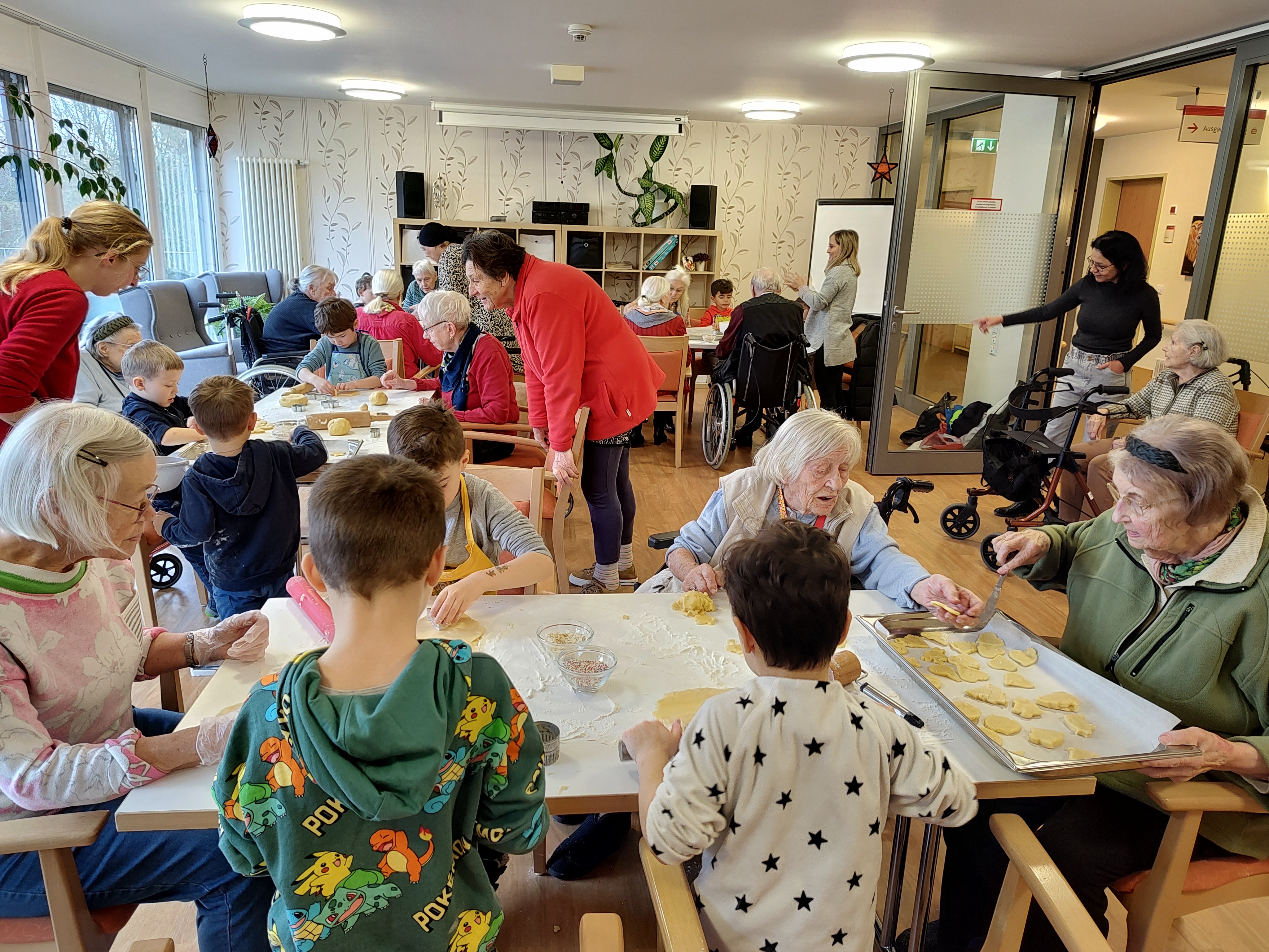 Viel Trubel: Seniorinnen und Kinder rollen an Tischen Teig aus.