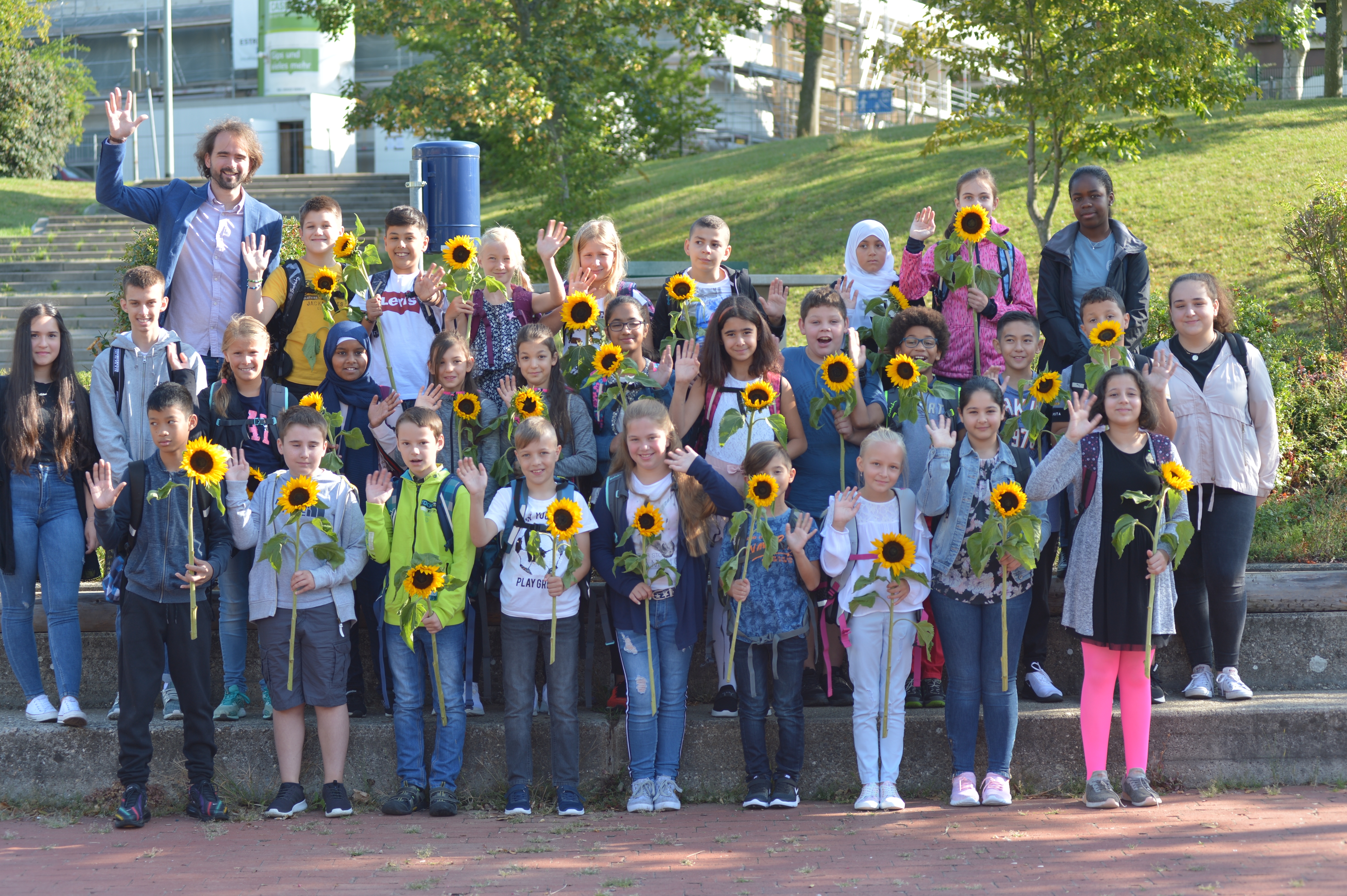 Die Klasse R5a mit Lehrer Ivo Reichert. Alle Schüler haben Sonnenblumen in der Hand.