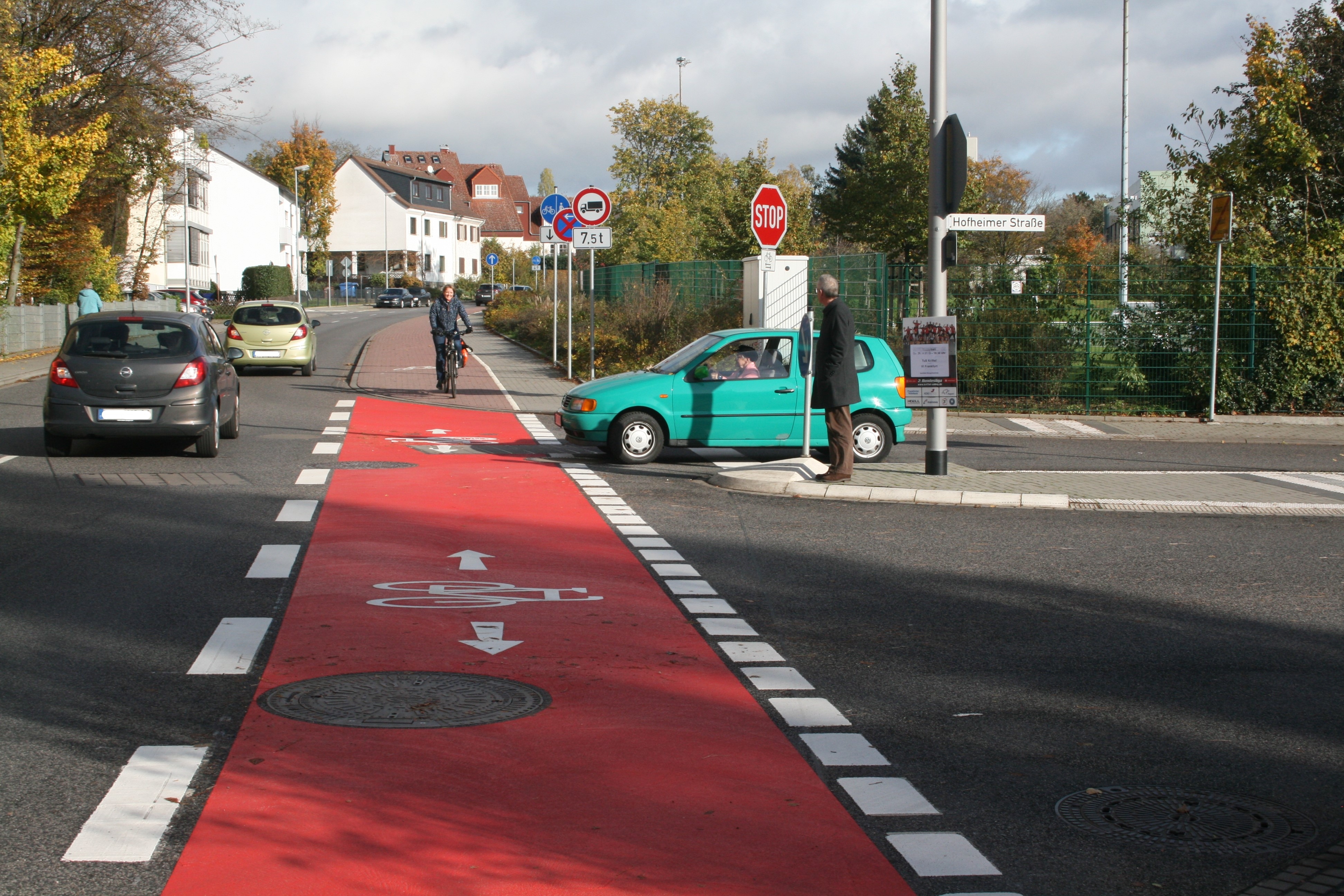 Eine Fahrradfahrerin auf dem Radweg am Schmelzweg kreuzt die Hofheimer Straße.