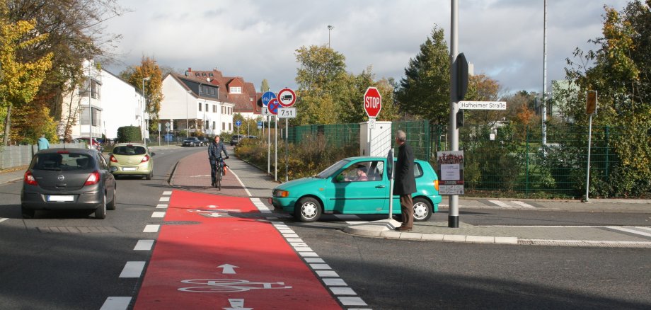 Eine Fahrradfahrerin auf dem Radweg am Schmelzweg kreuzt die Hofheimer Straße.