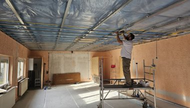Mann erneuert Decke im Vereinsheim.