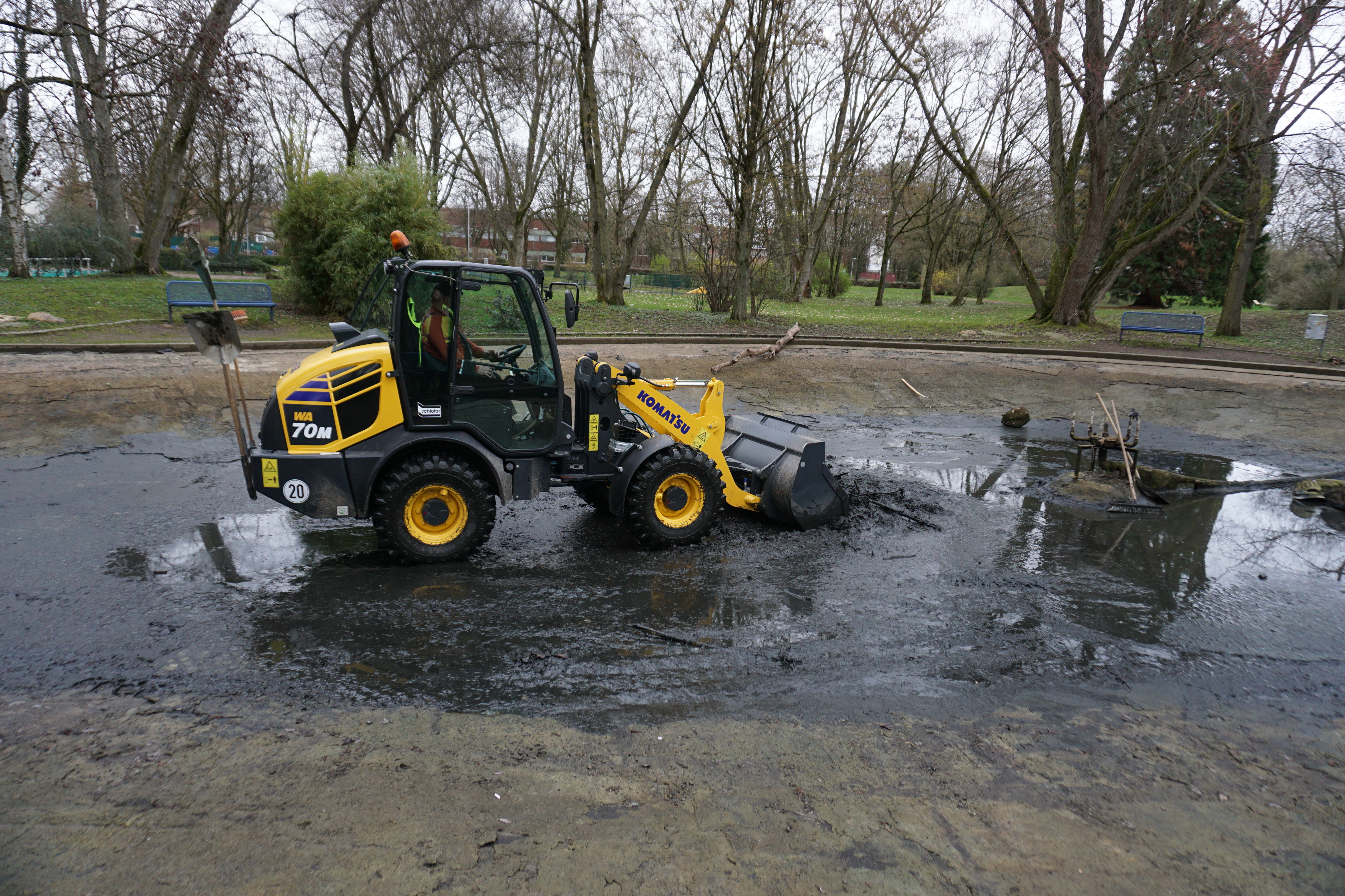 Mit einem Radlager wird Matsch aus dem Weiher-Becken geschaufelt.