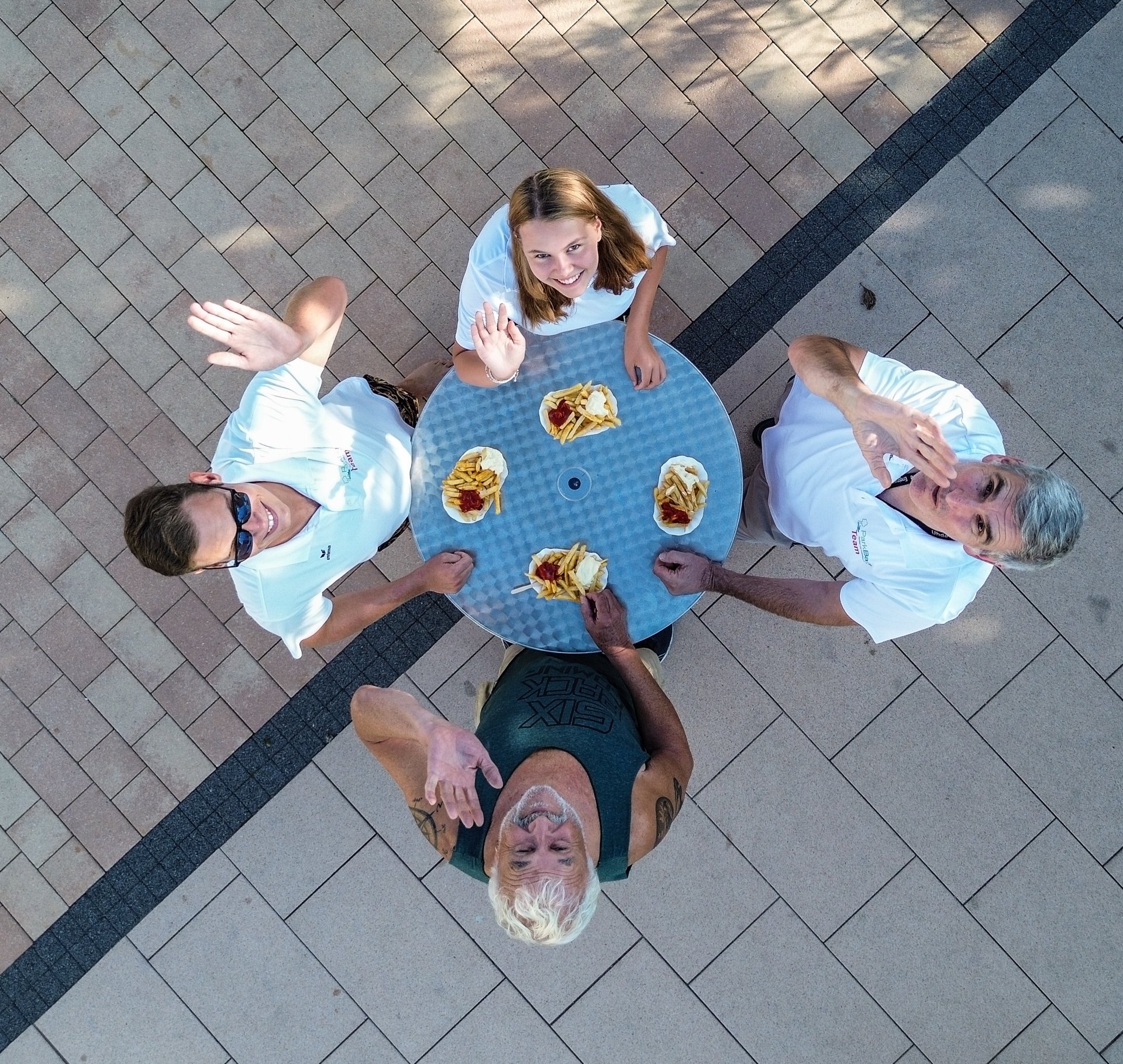 Vier Menschen essen Pommes. Aufnahme mit Drohne gemacht.