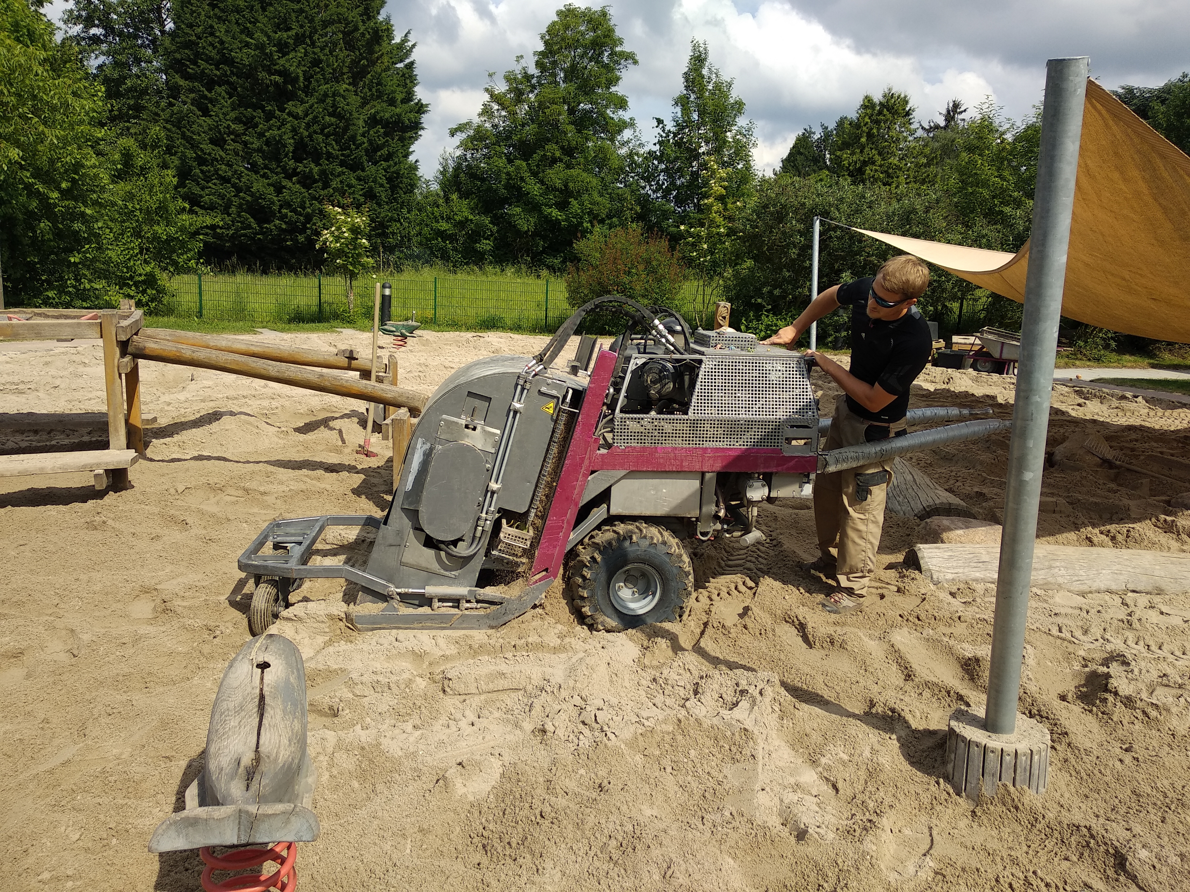 Mit einem kleinen Bagger wird der Sand gesiebt.