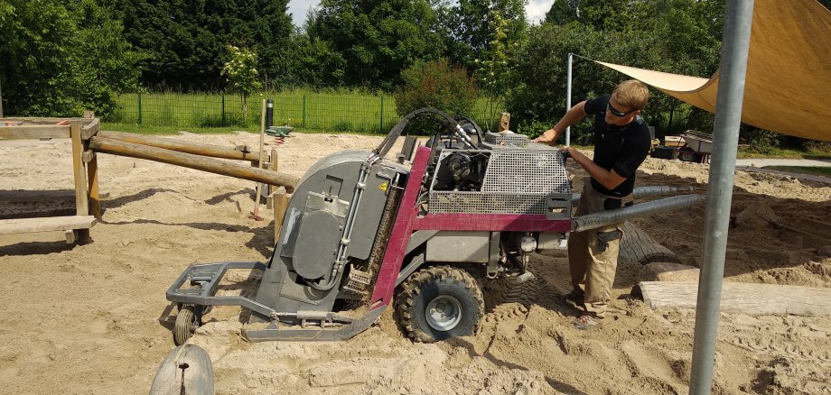 Mit einem kleinen Bagger wird der Sand gesiebt.