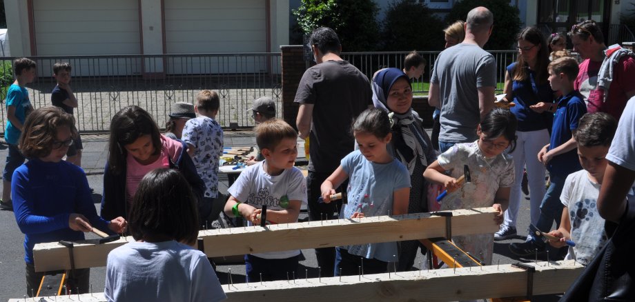 Kinder hämmern Nägel in einen Holzbalken.
