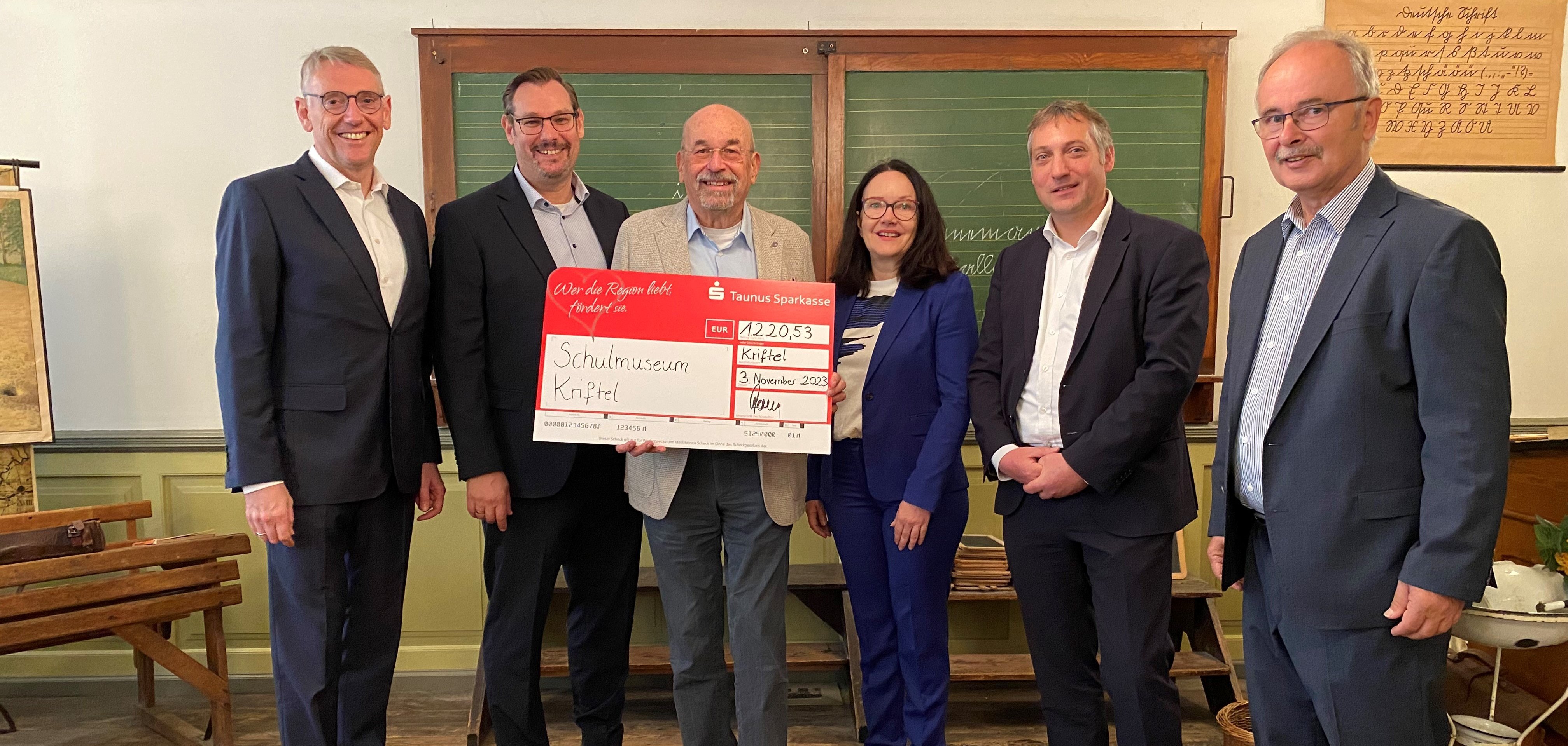 Museumsleiter mit Scheck inmitten der Offiziellen.