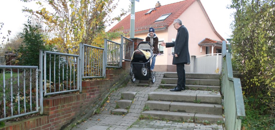 Eine Frau mit Kinderwagen hat Schwierigkeiten, die Treppenstufen am Hattersheimer Weg zu überwinden.