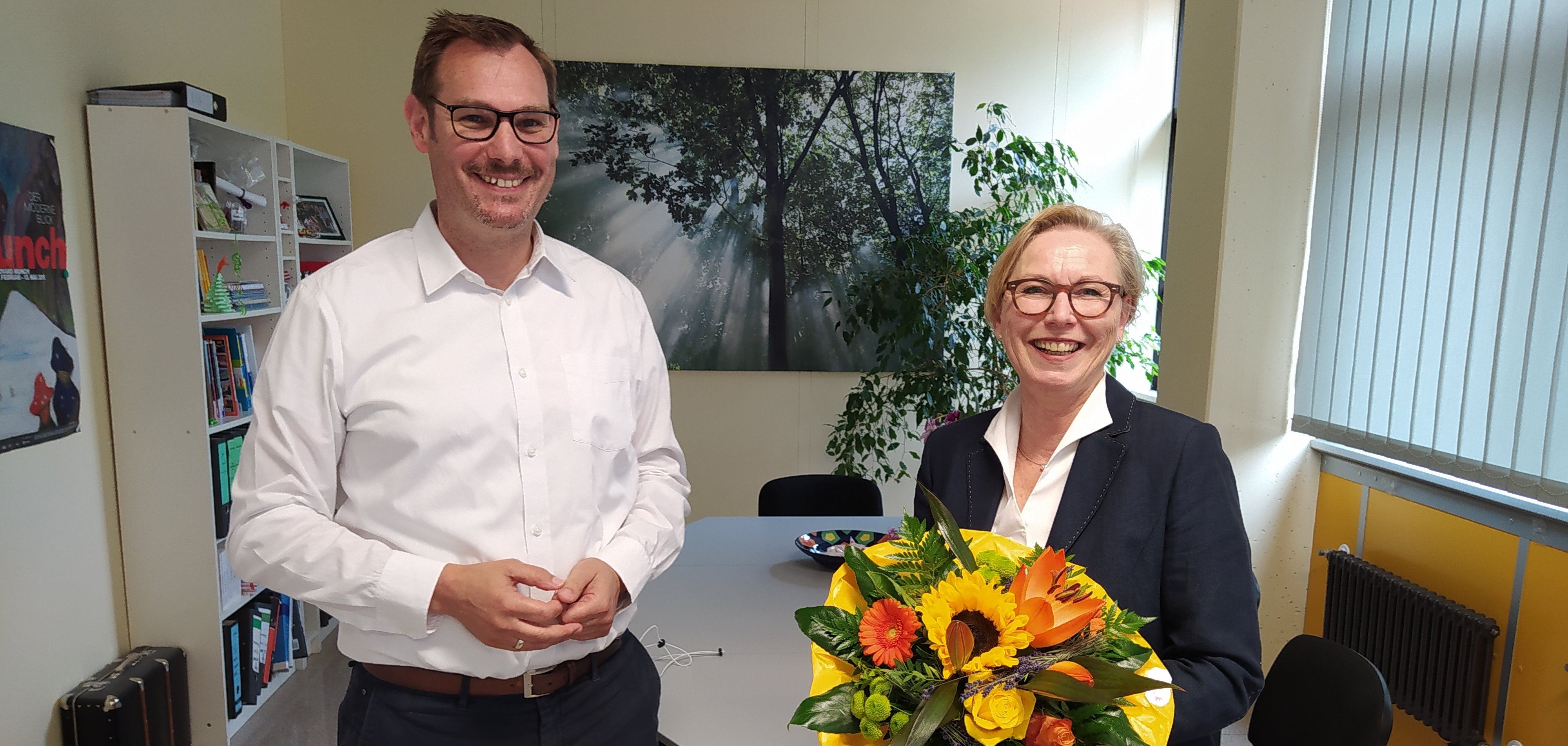Bürgermeister Seitz, Elke Wetterau-Bein in ihrem Büro mit Blumenstrauß in der Hand.