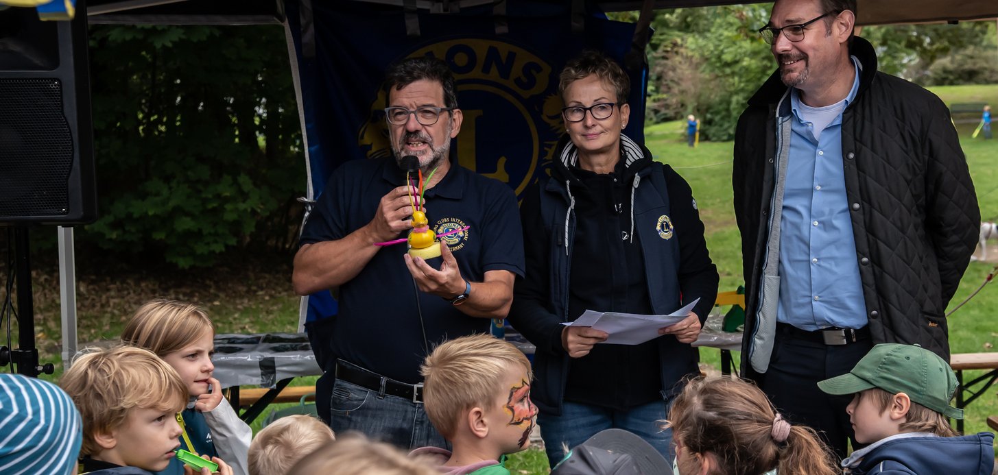 Bürgermeister und Vorsitzende des Lionsclub mit Ente bei der Siegerehrung Entenrennen.