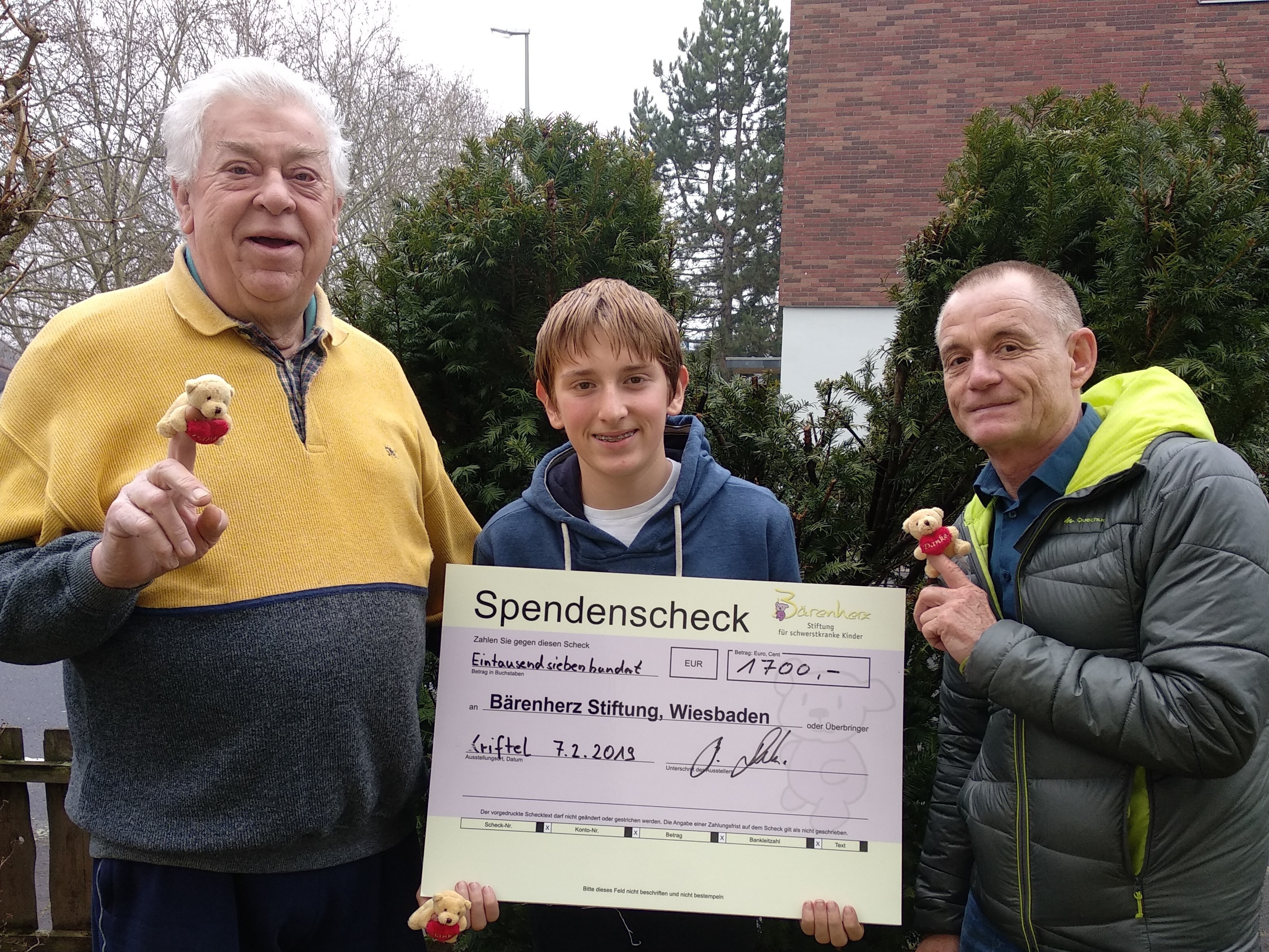 Bernhard Daubitz übergibt mit seinem Enkel den Spendenscheck an einen Vertreter von Bärenherz.