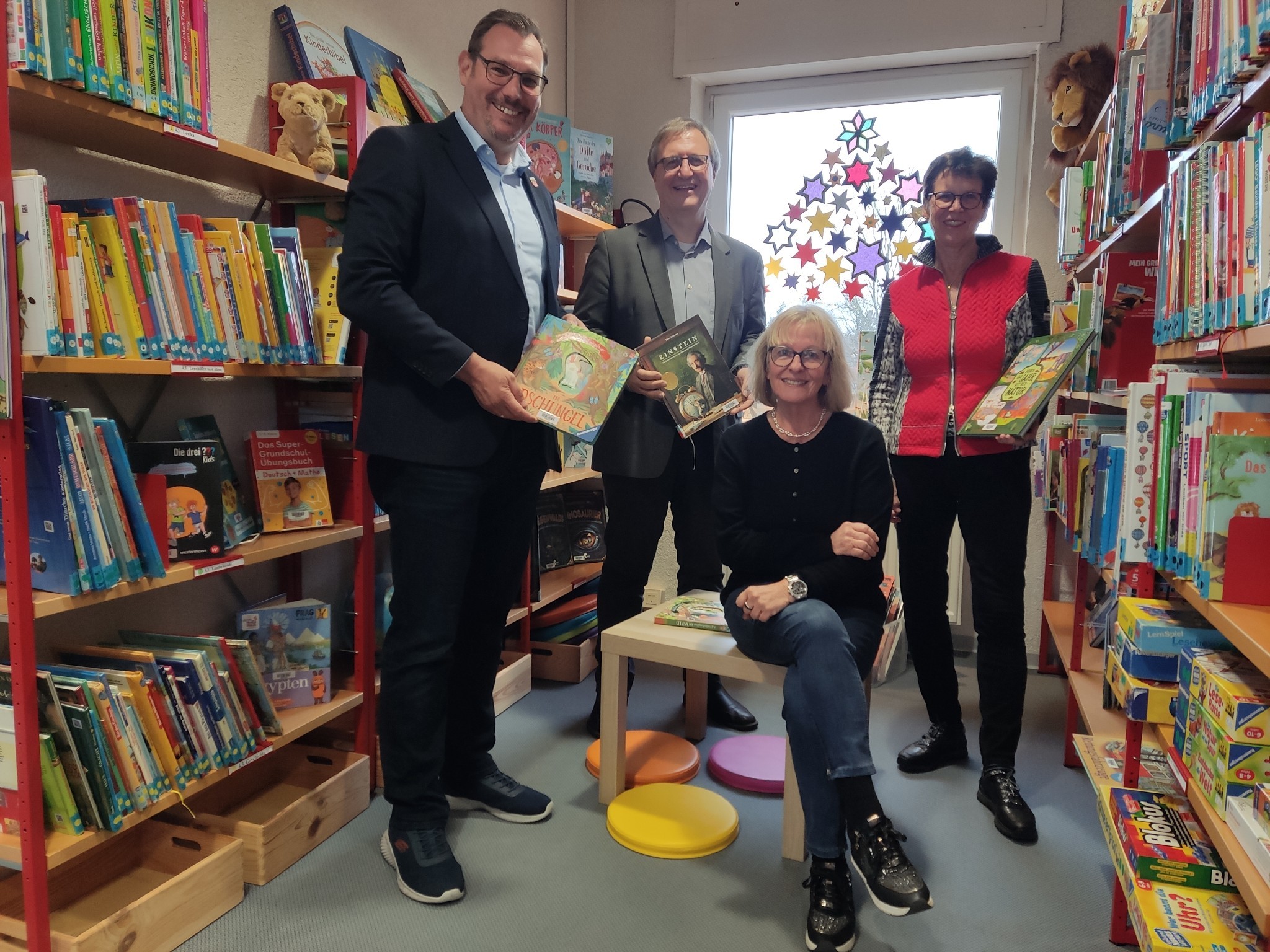 Bürgermeister, Dr. Fichert, Eva Momma und die Spenderin in der Leseecke.