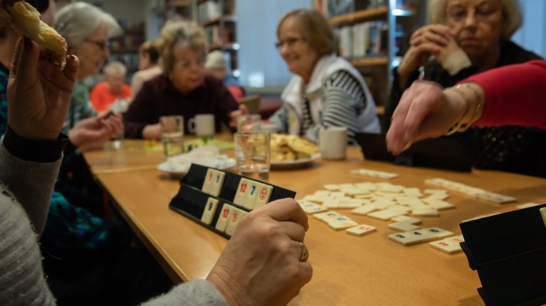 Eine Seniorengruppe spielt Rummicub.