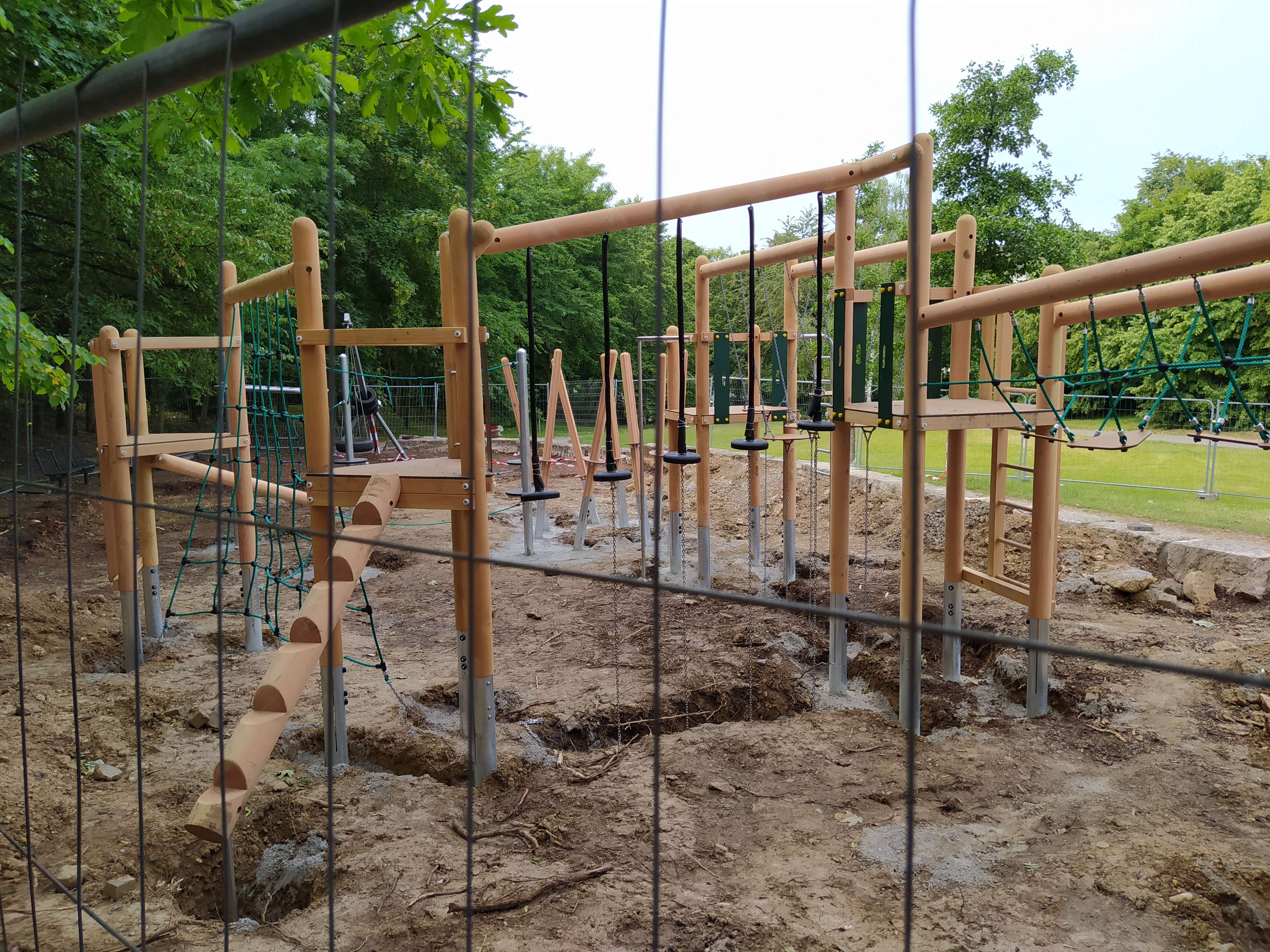Eine große Kletterlandschaft hinter einem Bauzaun.