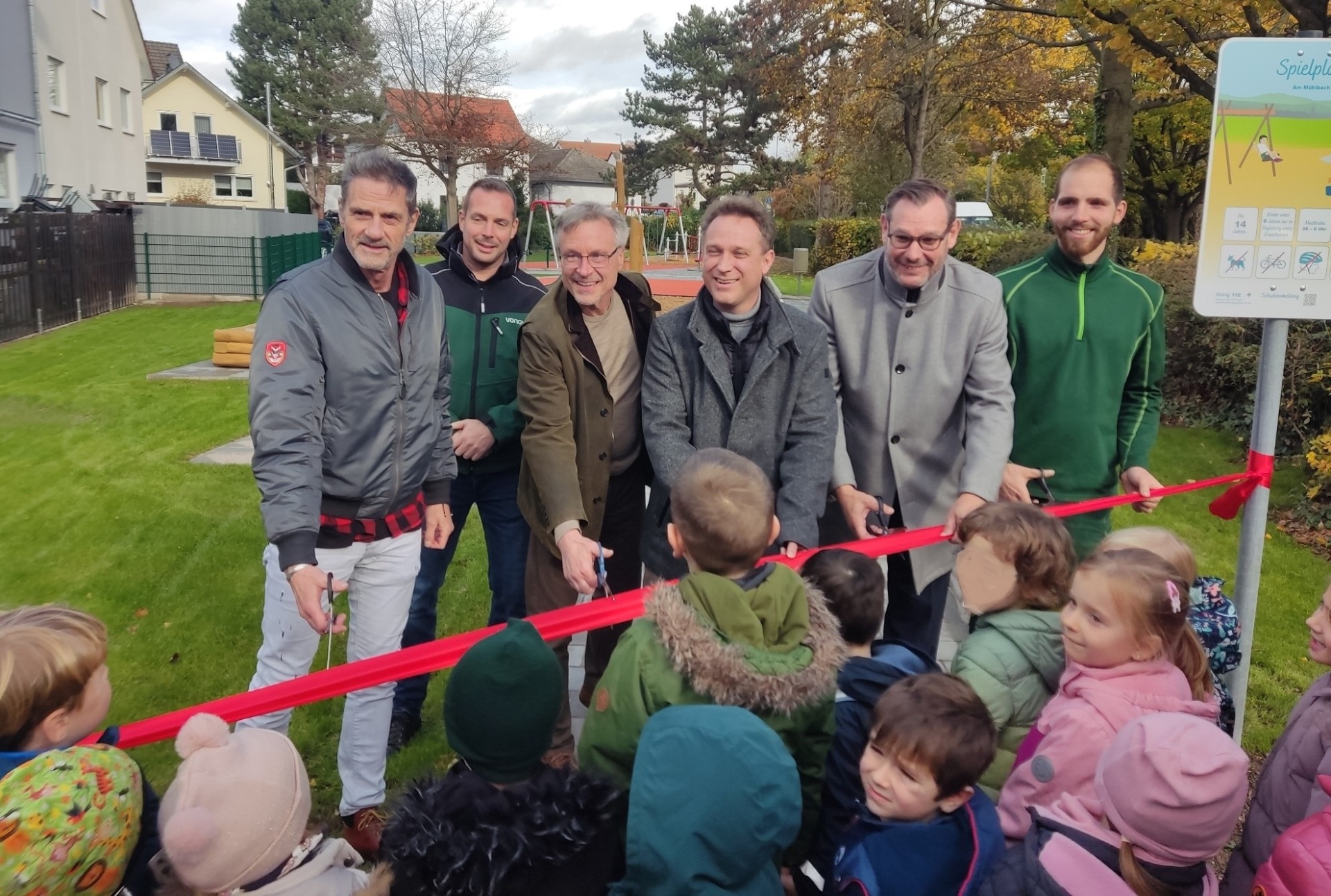 Bürgermeister und Beteiligte am Bau durchschneiden das rote Band.