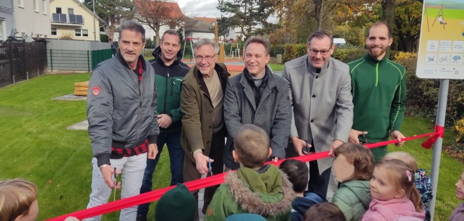 Bürgermeister und Beteiligte am Bau durchschneiden das rote Band.