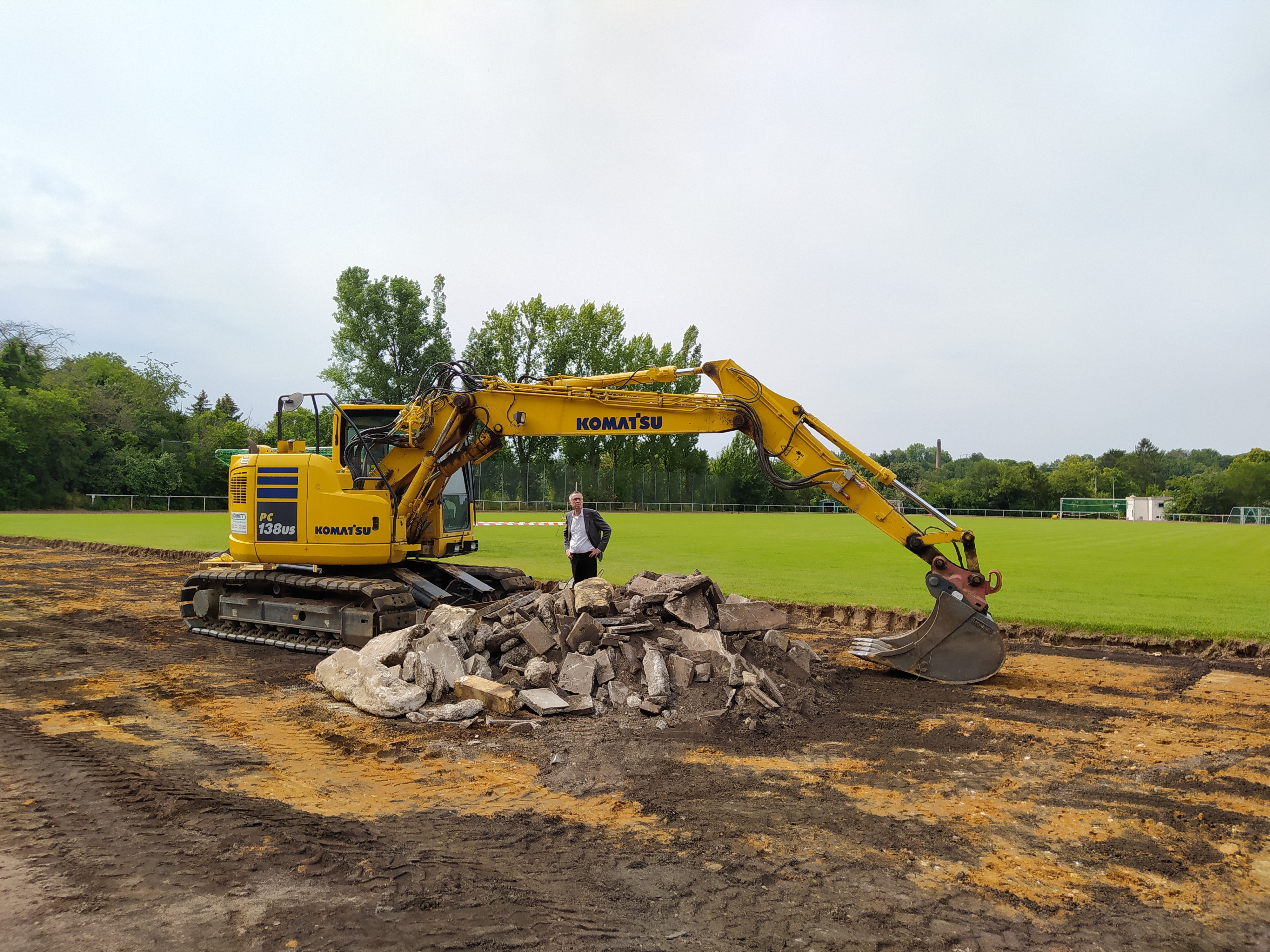 Franz Jirasek neben einem Bagger und einem Erdhaufen auf dem Sportplatz.