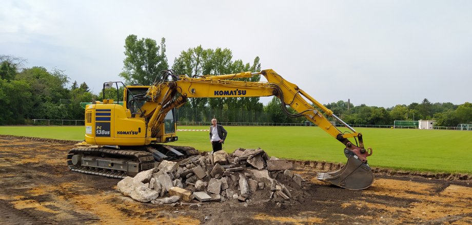 Franz Jirasek neben einem Bagger und einem Erdhaufen auf dem Sportplatz.