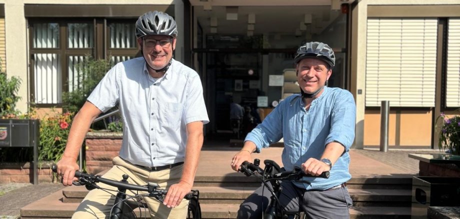 Seitz und Mohr auf dem Fahrrad vor dem Rathaus.