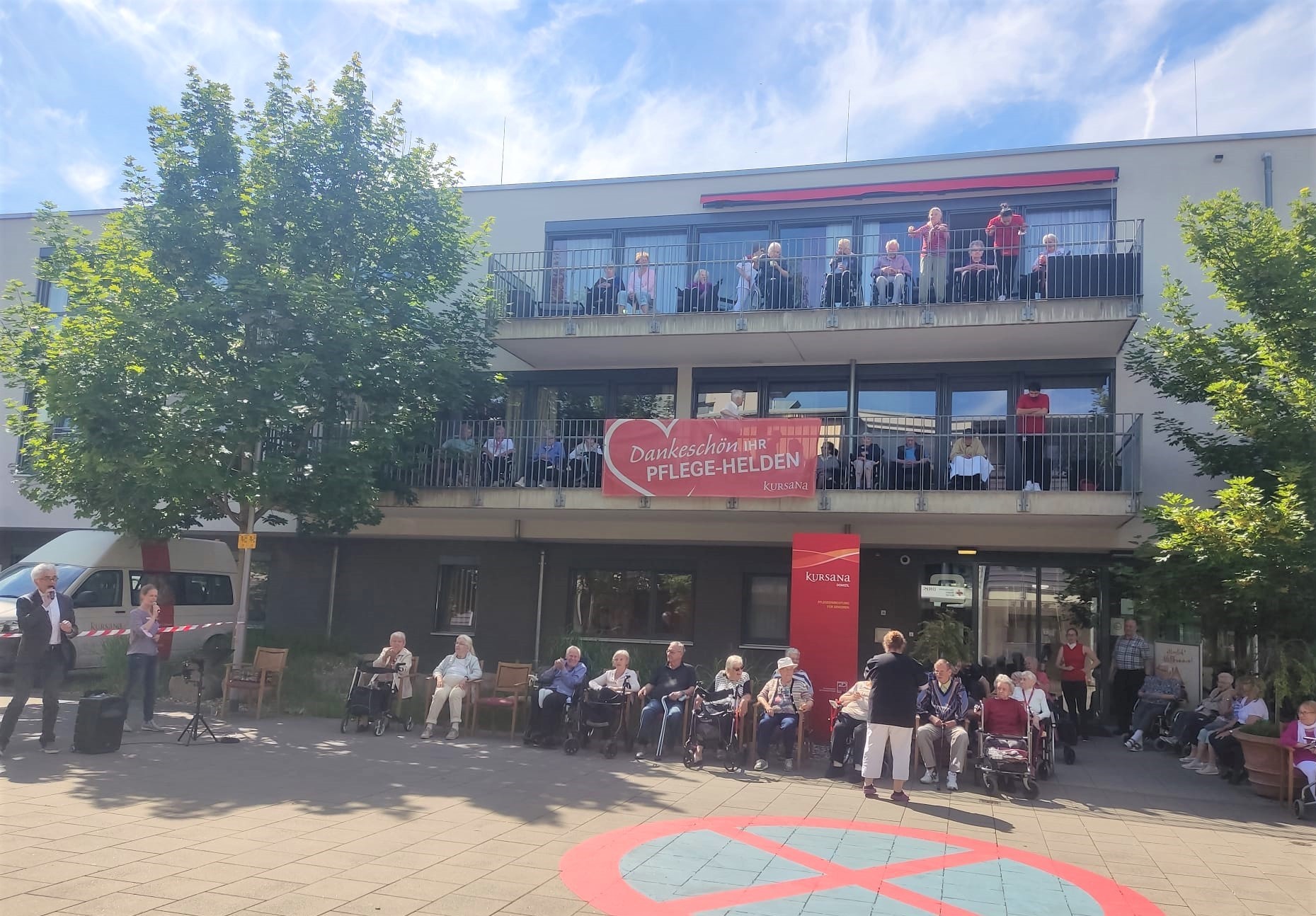 Das Seniorenheim mit vielen Menschen auf den Balkonen.