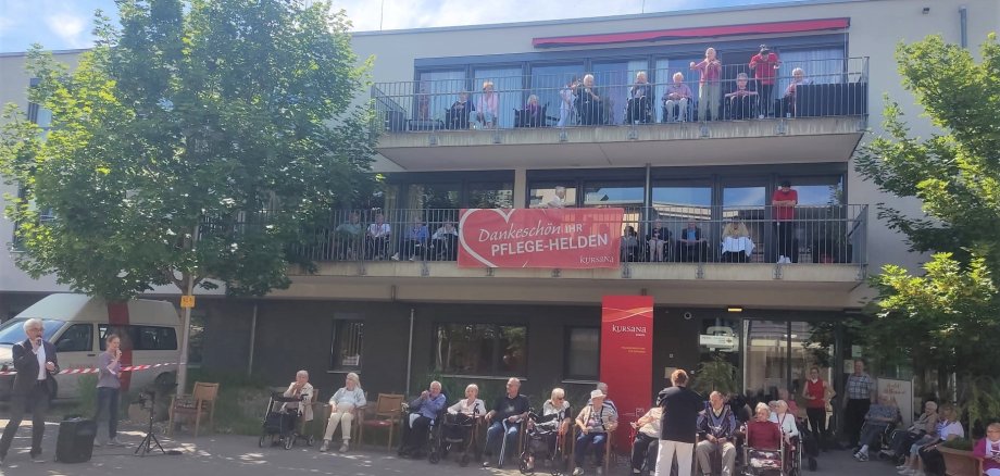 Das Seniorenheim mit vielen Menschen auf den Balkonen.