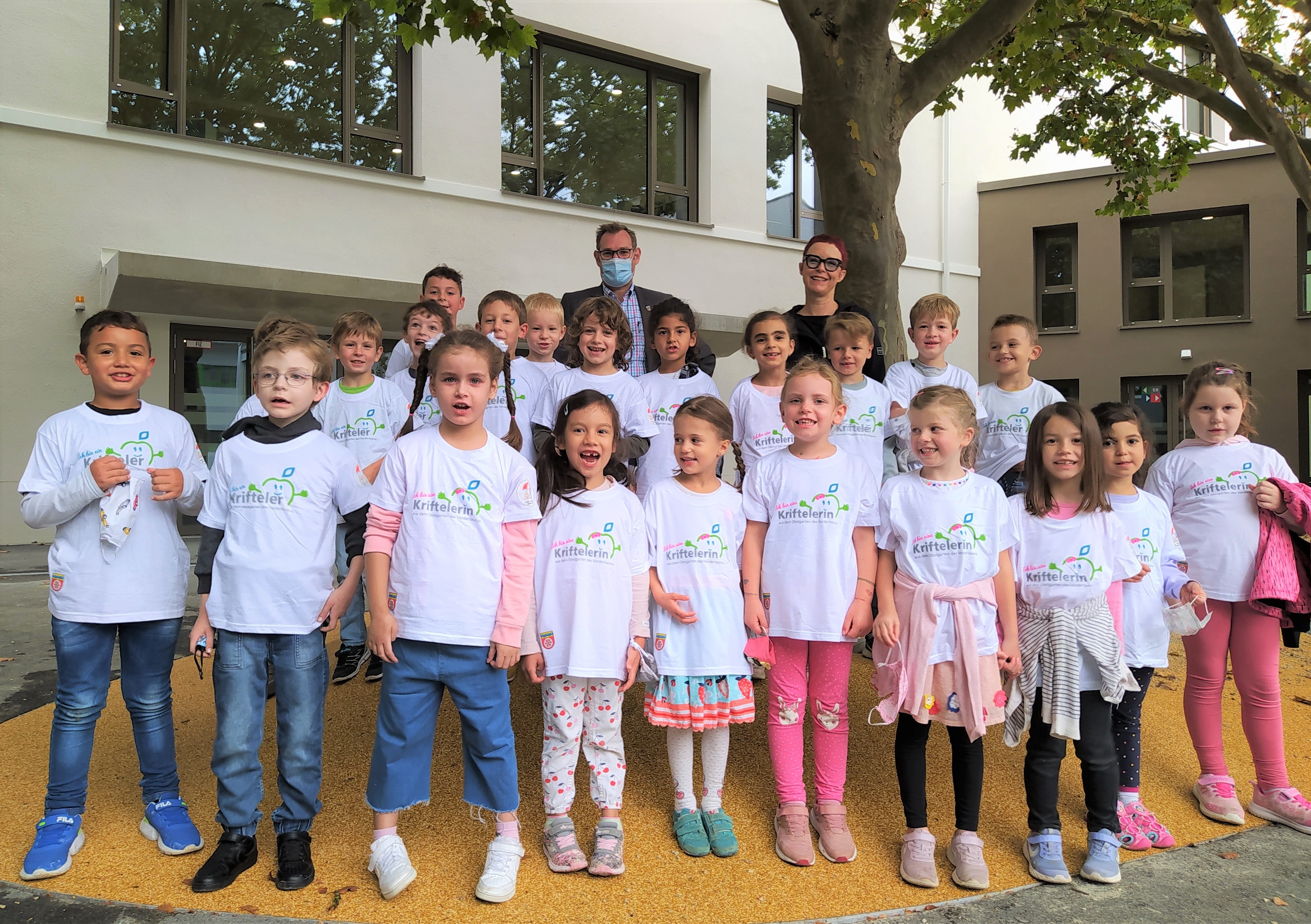 Die Klasse 1d mit Bürgermeister und Gemeinde-T-Shirts auf dem Schulhof.