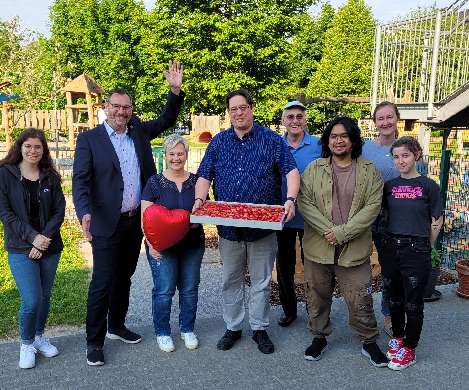Bürgermeister und Kita-Team mit Kuchen und Ballon.